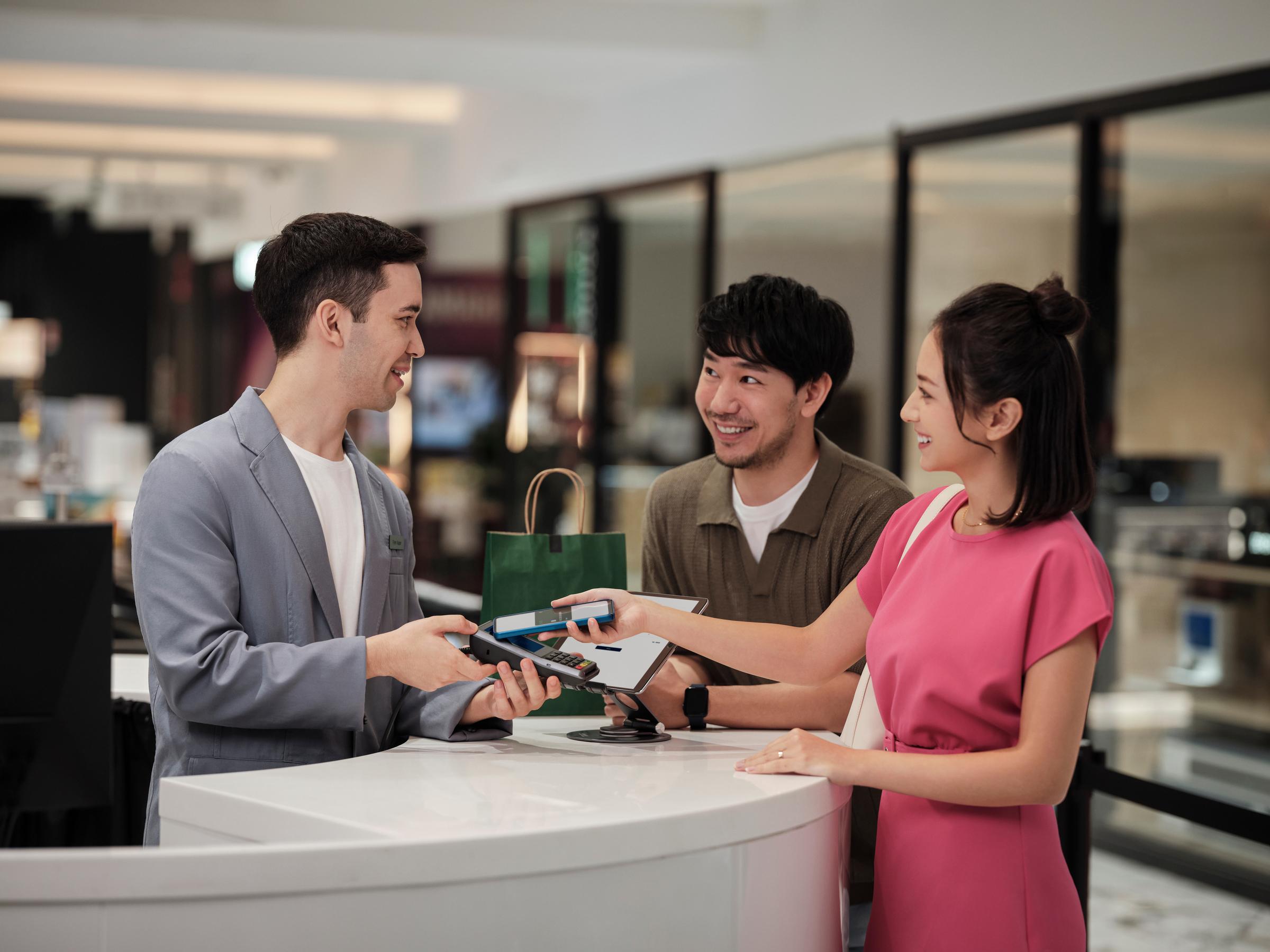 Asian couple paying with mobile phone at departmental store