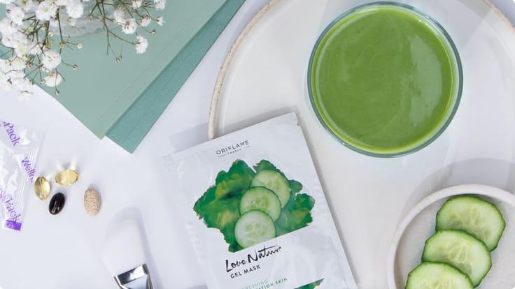 Produkty wellness, w tym suplementy, maska żelowa i zielony smoothie na białej powierzchni.