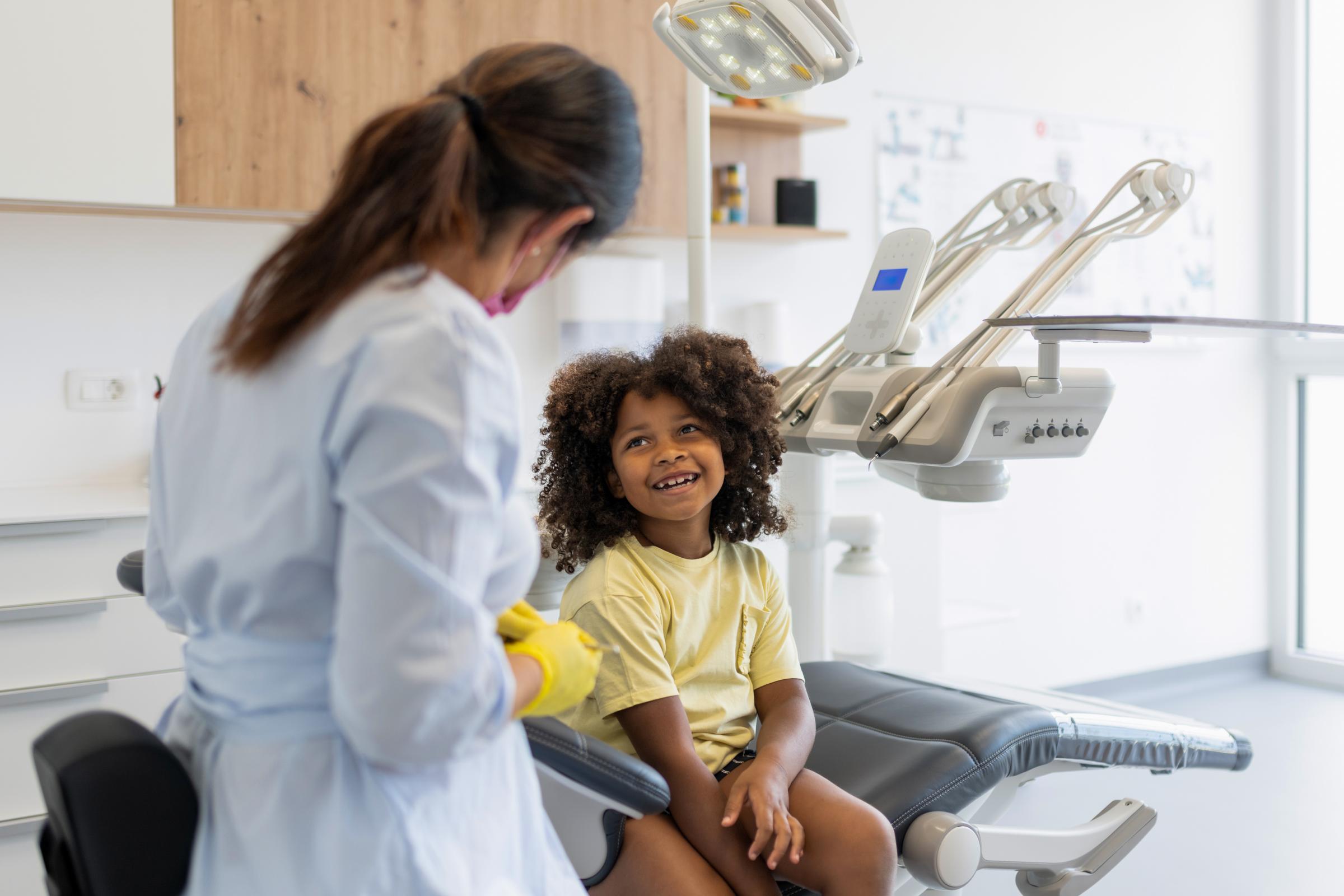 A children's dentist talks with child patient in the dental chair