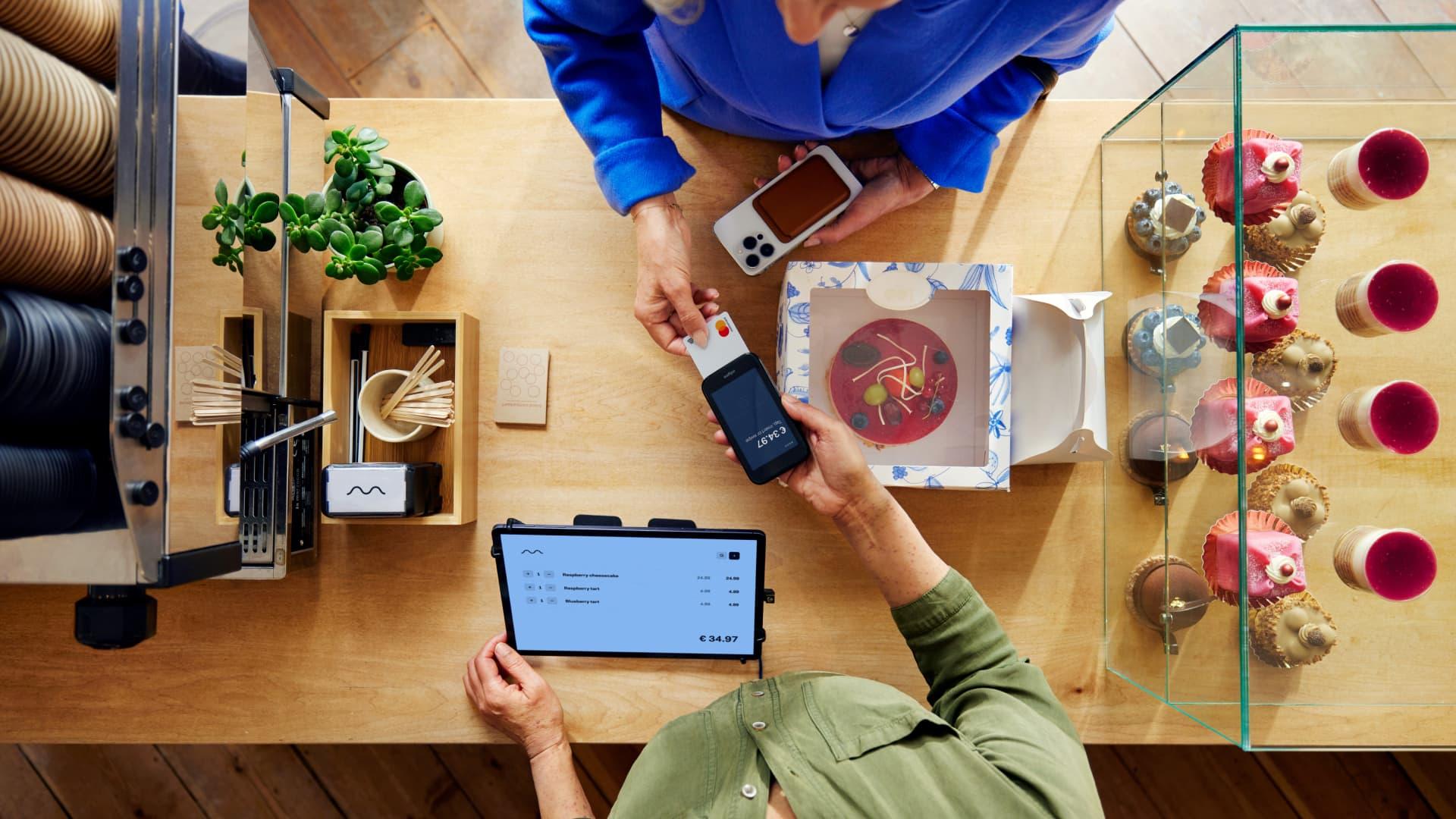 Personne utilisant un téléphone portable pour effectuer un paiement sans contact via le terminal Adyen.