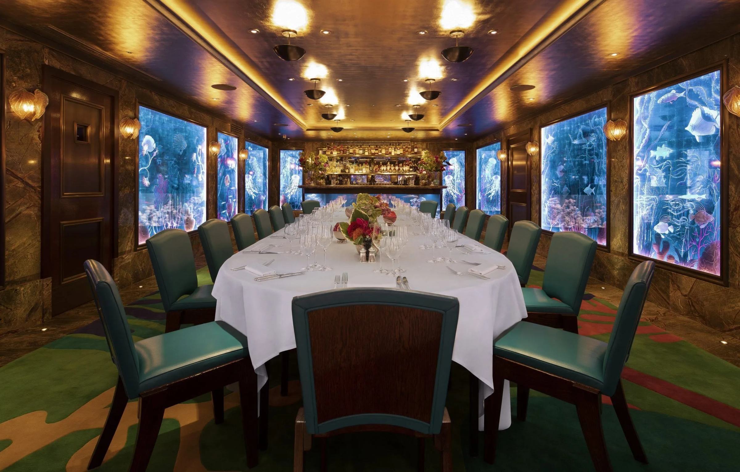 A big dressed table in a restaurant with green chairs 