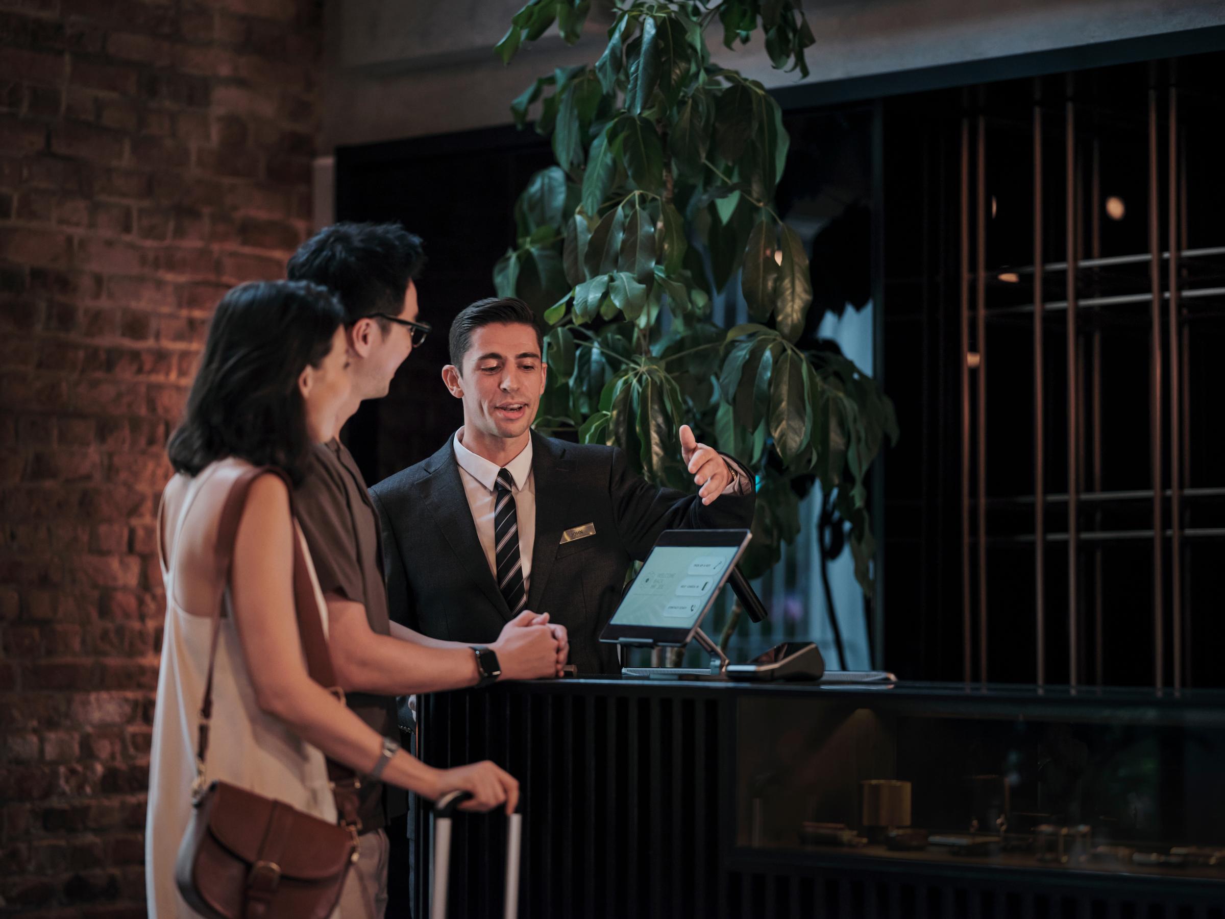 A couple checking into a hotel room at reception desk.