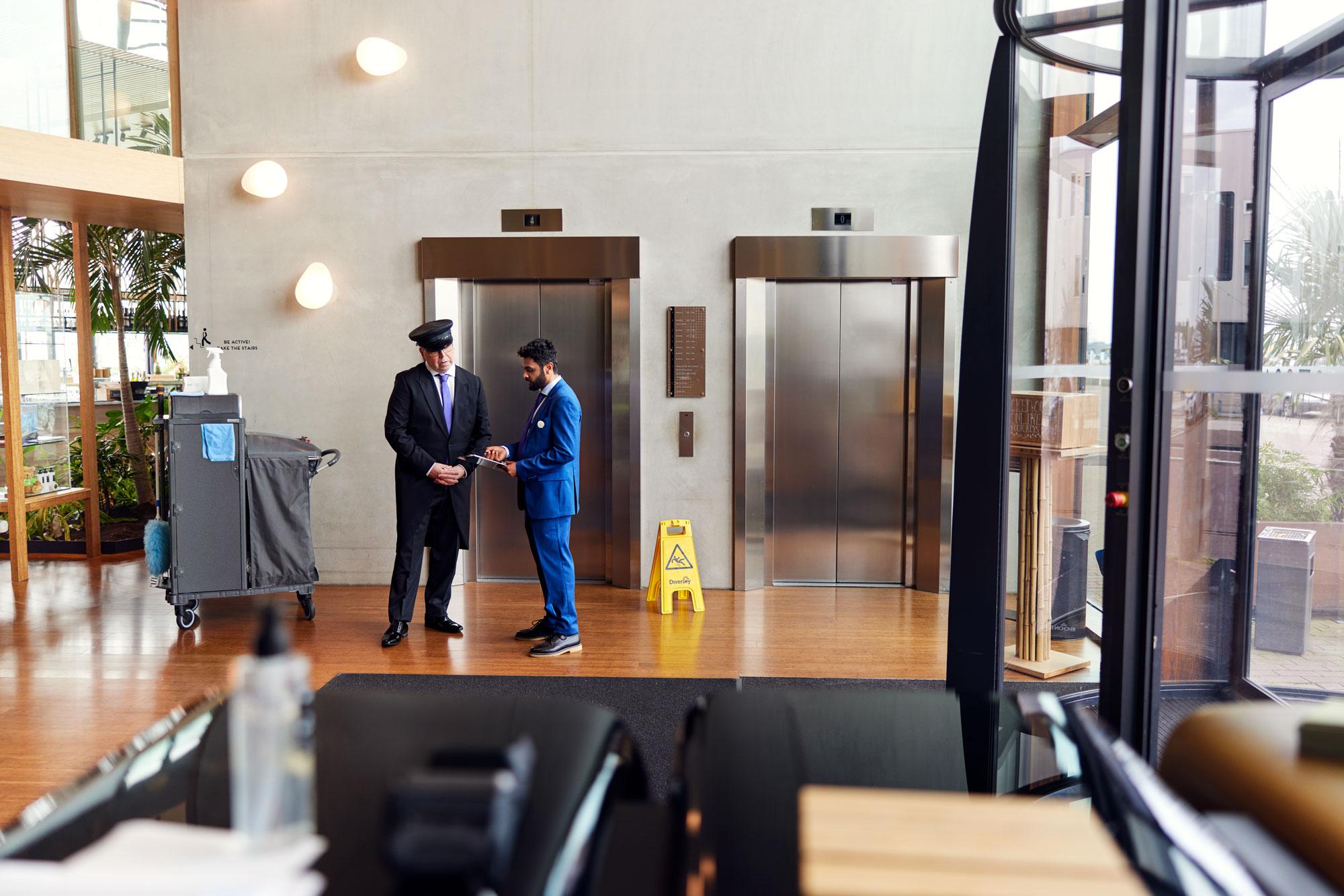 Dos empleados de hotel discutiendo y preparando el vestíbulo del hotel para los huéspedes.