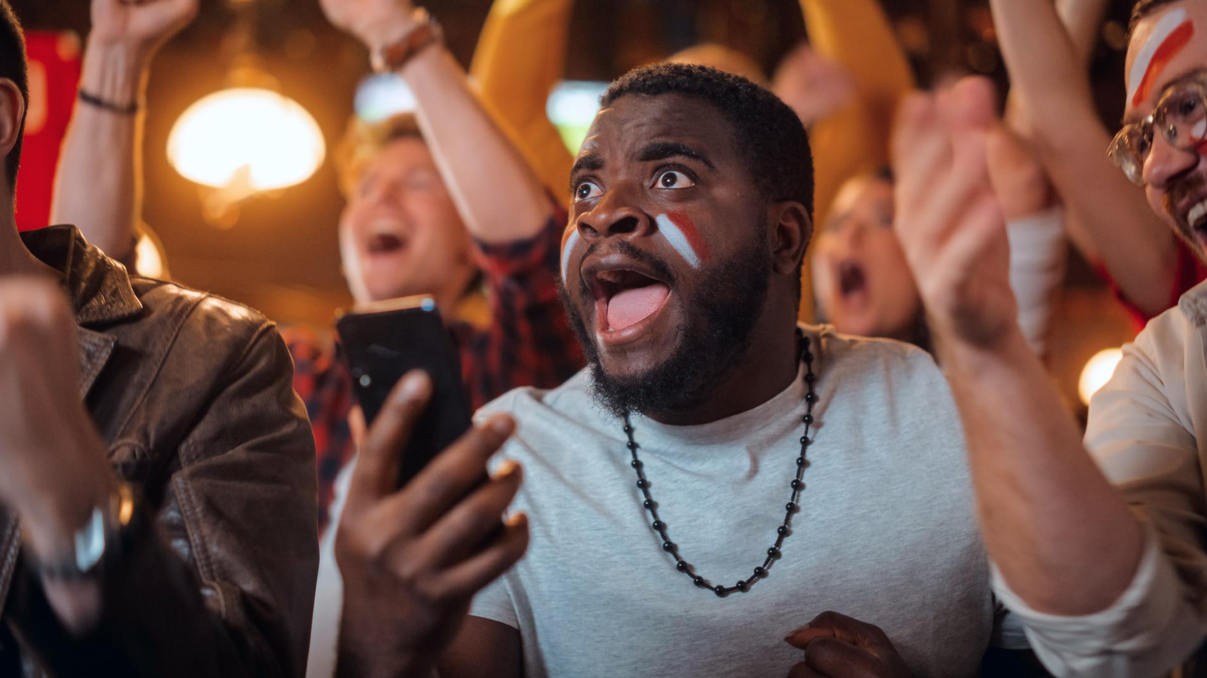 Man in cheering in the crowd with his phone in his hand