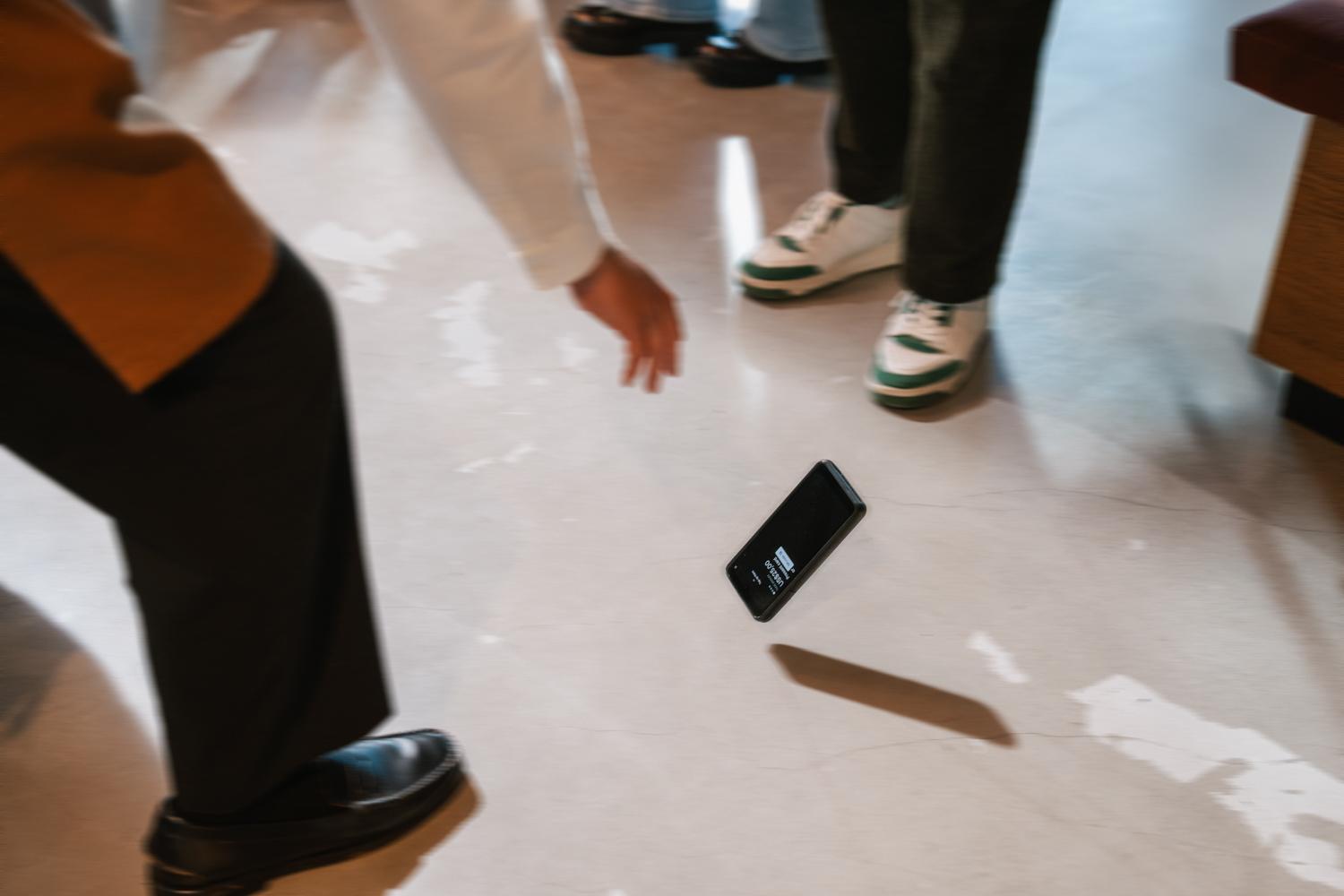 People using a mobile device with an Adyen payment terminal nearby on a smooth floor.
