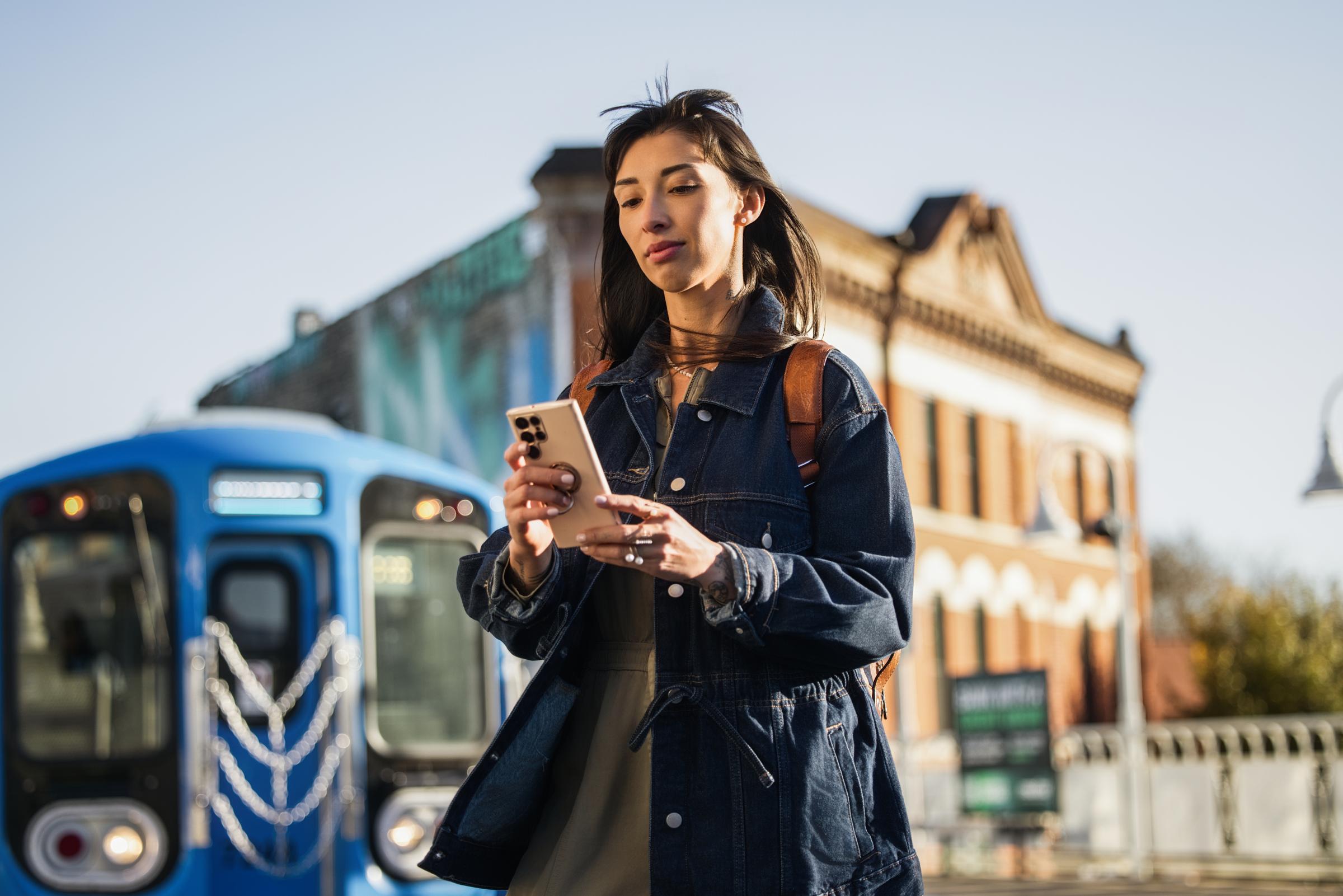 A person using a smartphone near an Adyen payment terminal on the street.