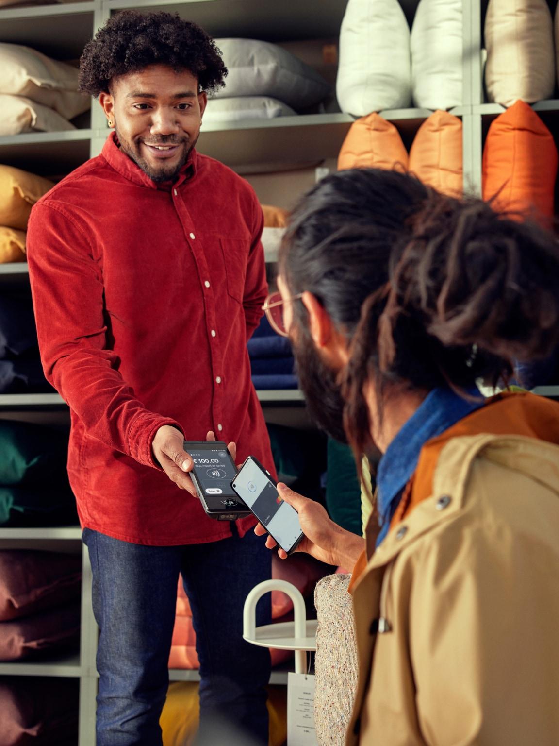 Dwie osoby dokonujące płatności przy użyciu urządzenia mobilnego punktu sprzedaży