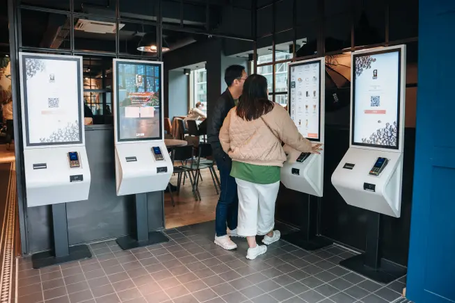 Adyen customers using self-service kiosks for payment transactions at a Coffee Fellows cafe.