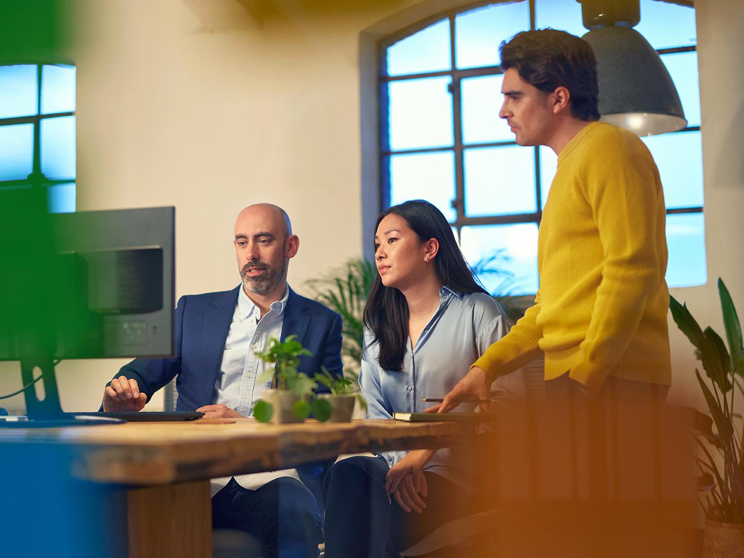 Three colleagues in an office looking at a screen together
