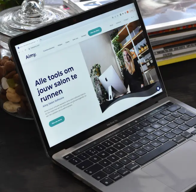 Laptop met een website met een vrouw die in een salon staat en salonbeheertools promoot