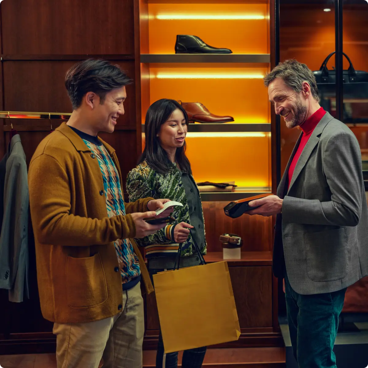 Two customers making a contactless payment with a clerk at a shoe store.
