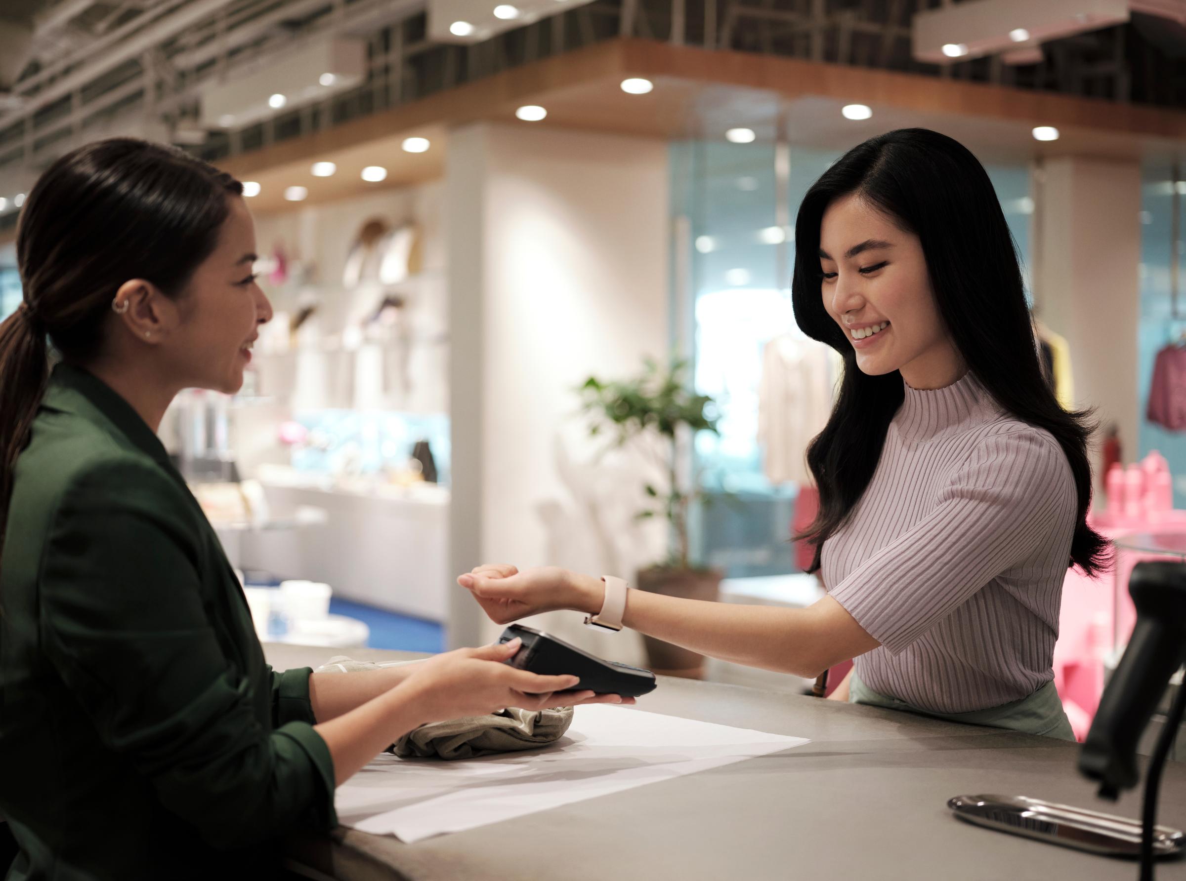 Woman shopping and paying inside a clothing and fashion store for apparel.