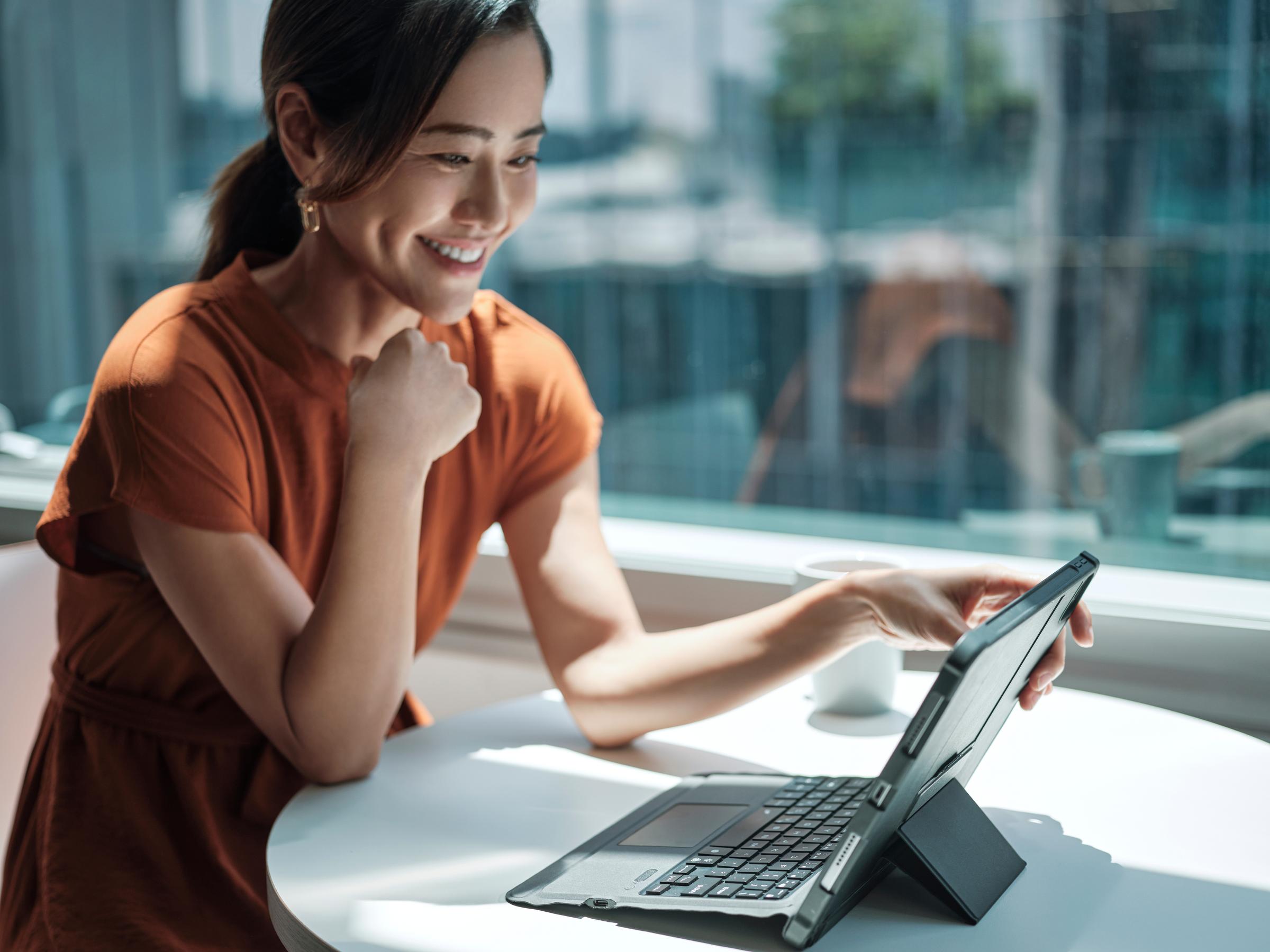A close up of a woman at a table working on her ipad