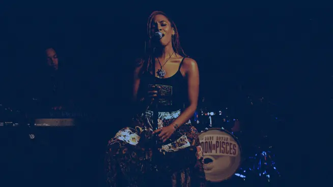 A woman singing on a stage into a microphone 