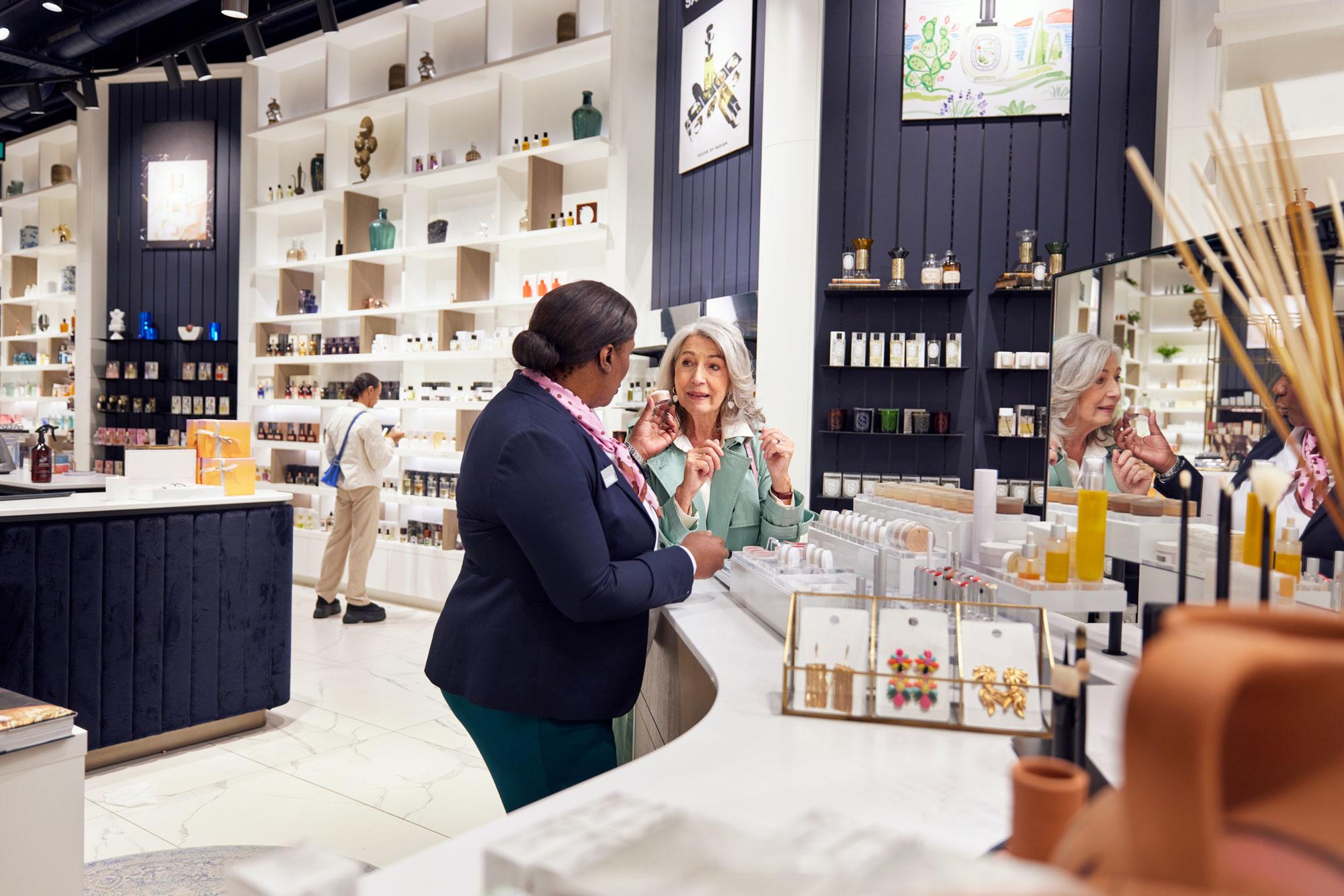 En kunde i en kosmetikbutik diskuterer skønhedsprodukter med en medarbejder.