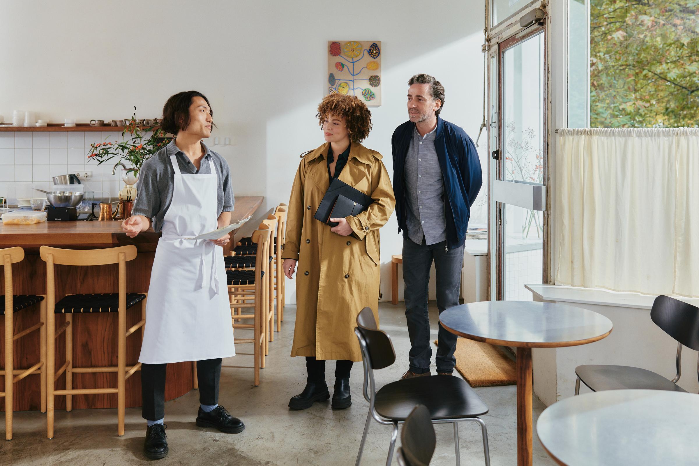Un couple dans un restaurant accueilli par un serveur.