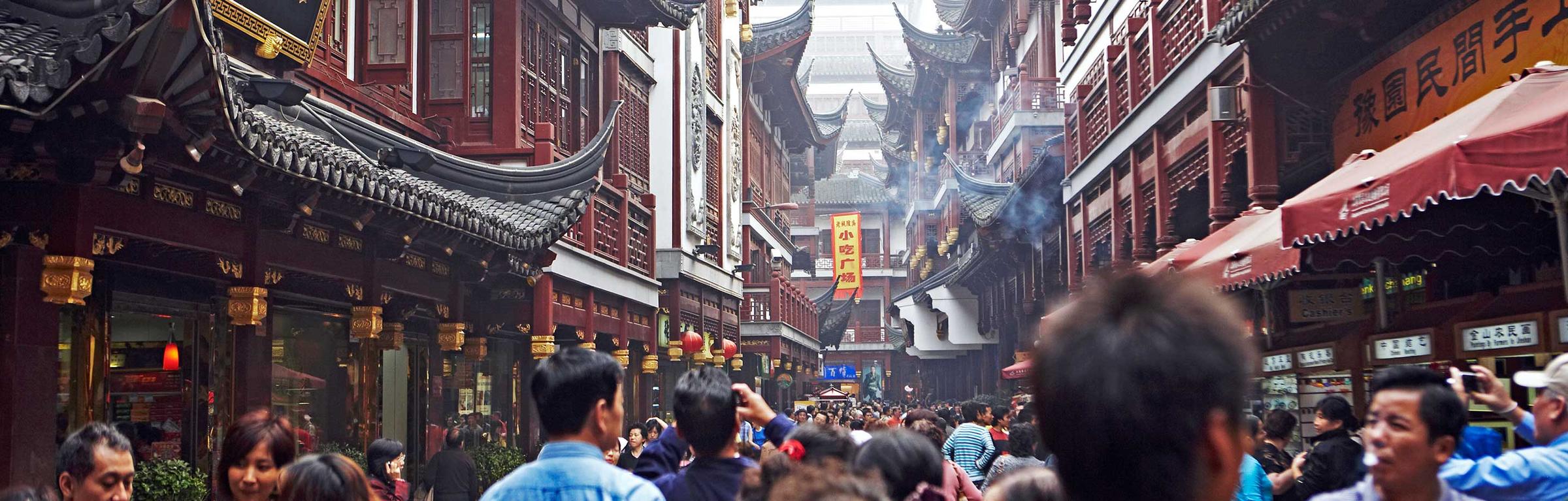 Busy traditional Chinese street with crowded shops and red lanterns.