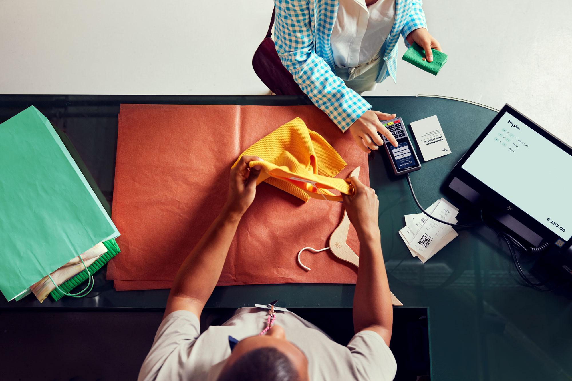 Une femme dans un magasin de vêtements payant et faisant un don sur le terminal P400 d'Adyen.