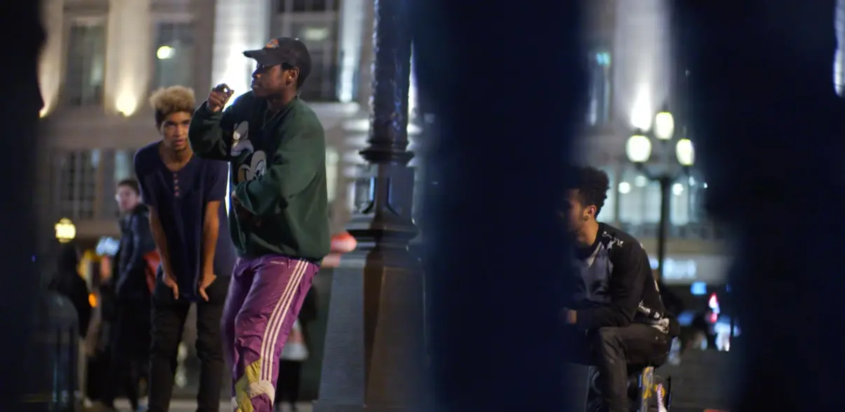 Group of young adults gathered on a city street at night.