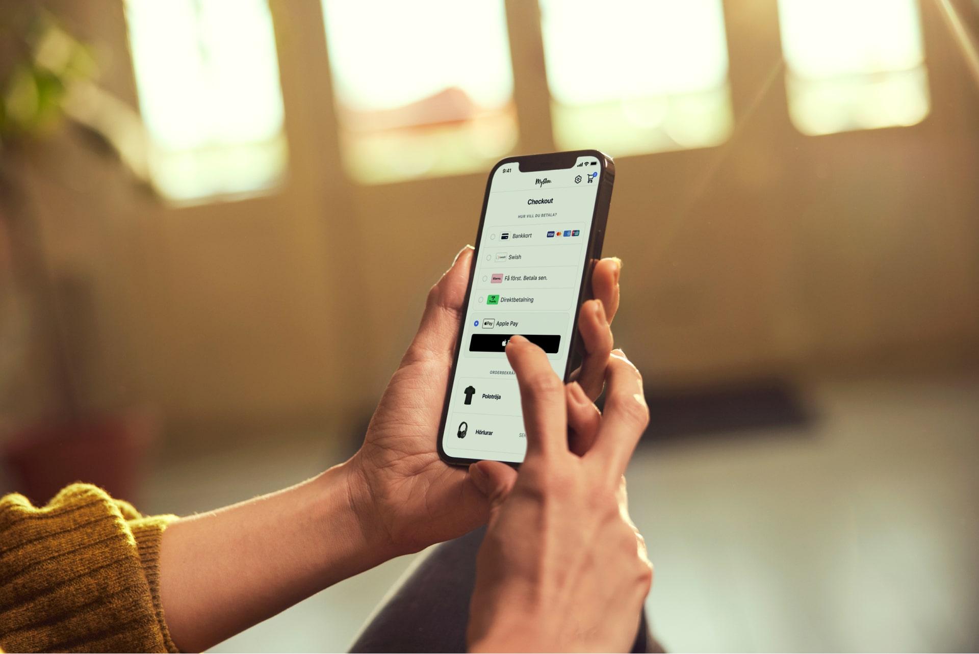 Närbild av händer som håller en smartphone med Adyens betalningsgränssnitt.