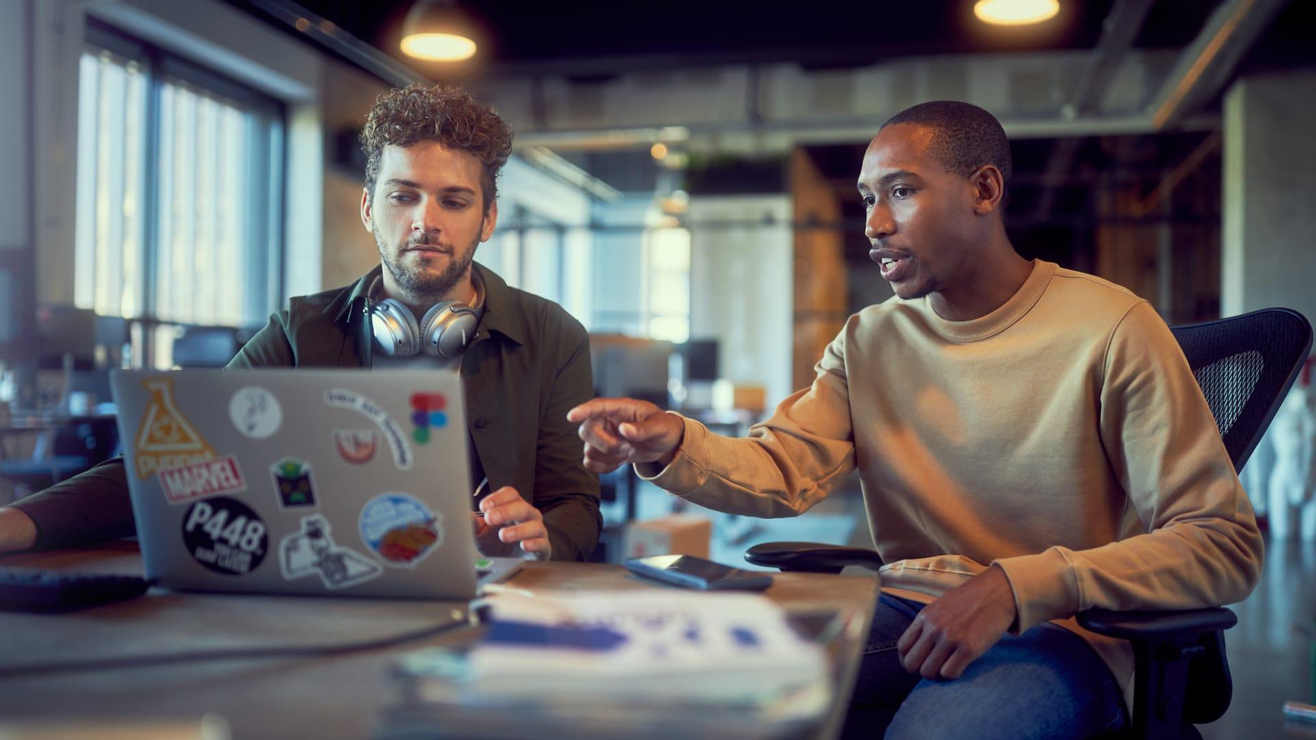 Two colleagues discussing over a laptop in a modern office space.