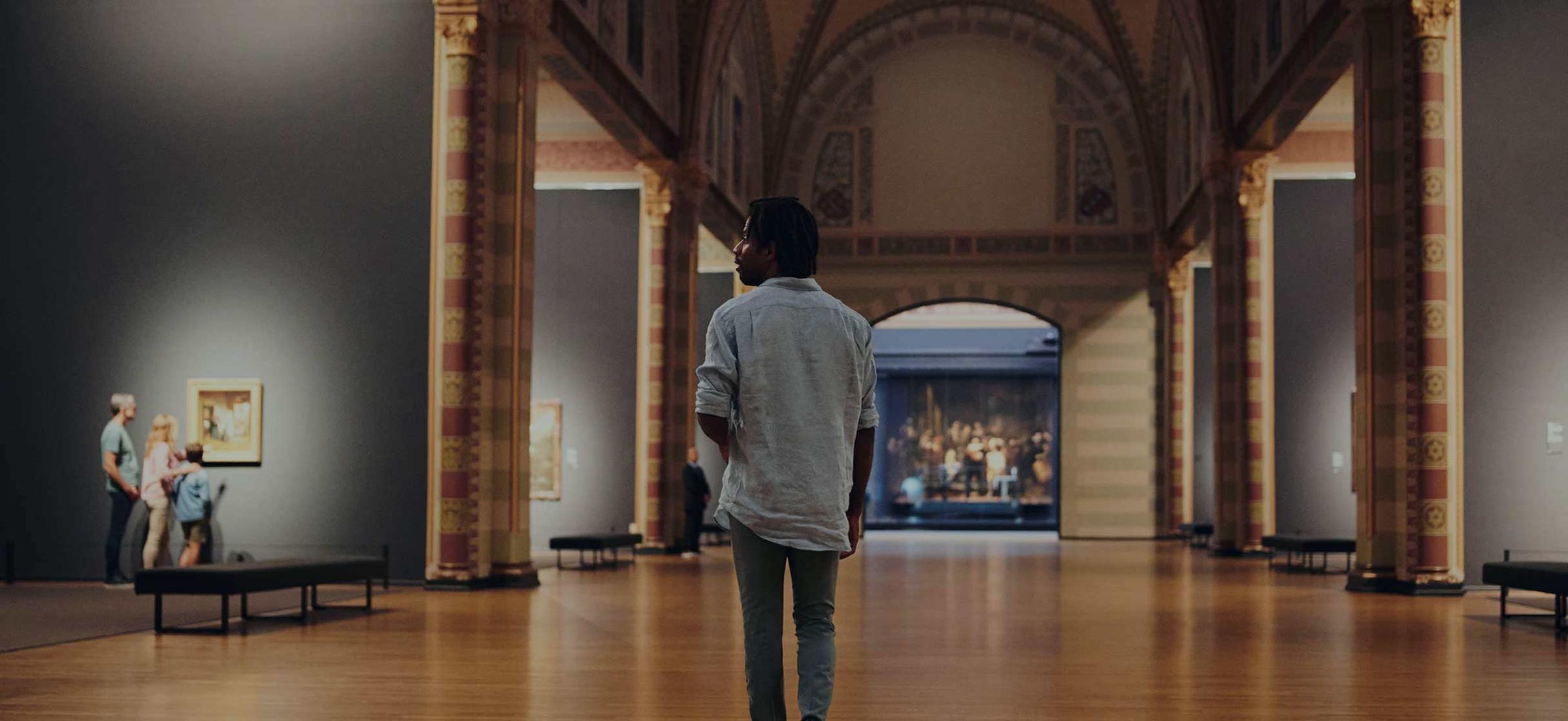 Man loopt door kunstgalerij en bekijkt schilderijen