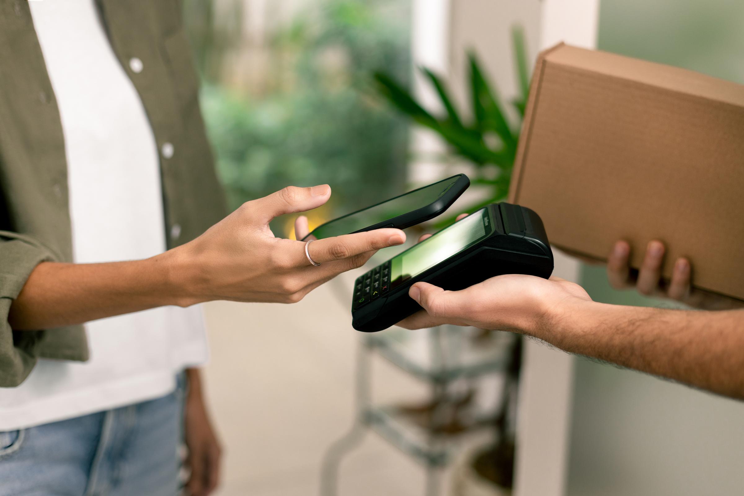 pagamento móvel com terminal de ponto de venda Adyen enquanto segura uma caixa