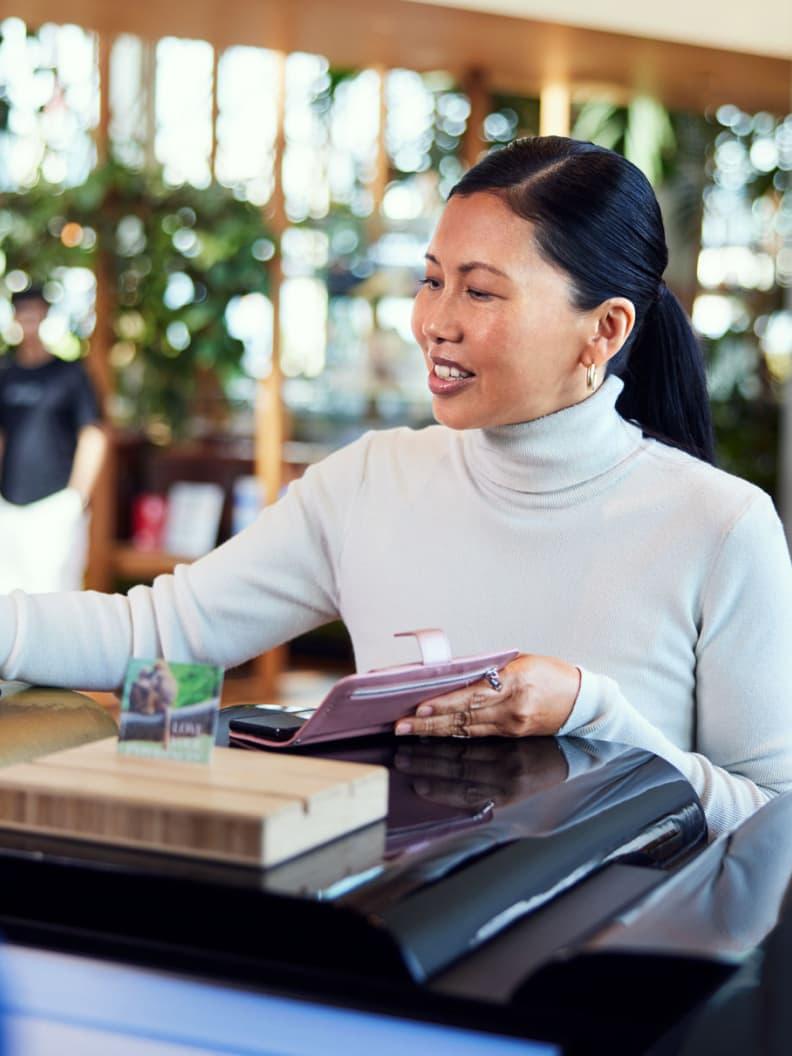 Woman holding wallet at checkout with Adyen terminal visible.