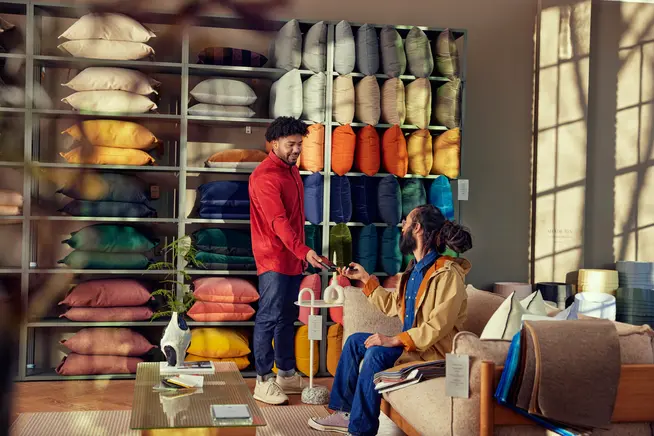 A man in a furniture store paying for home accessories by tapping a phone at an Adyen terminal.