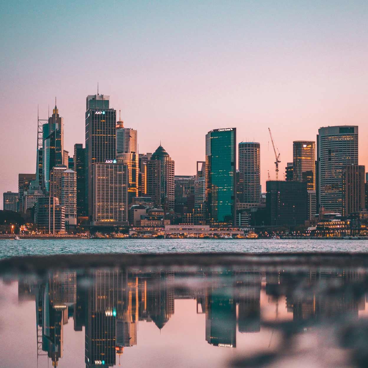 Twilight byskyline reflekteret i roligt vand