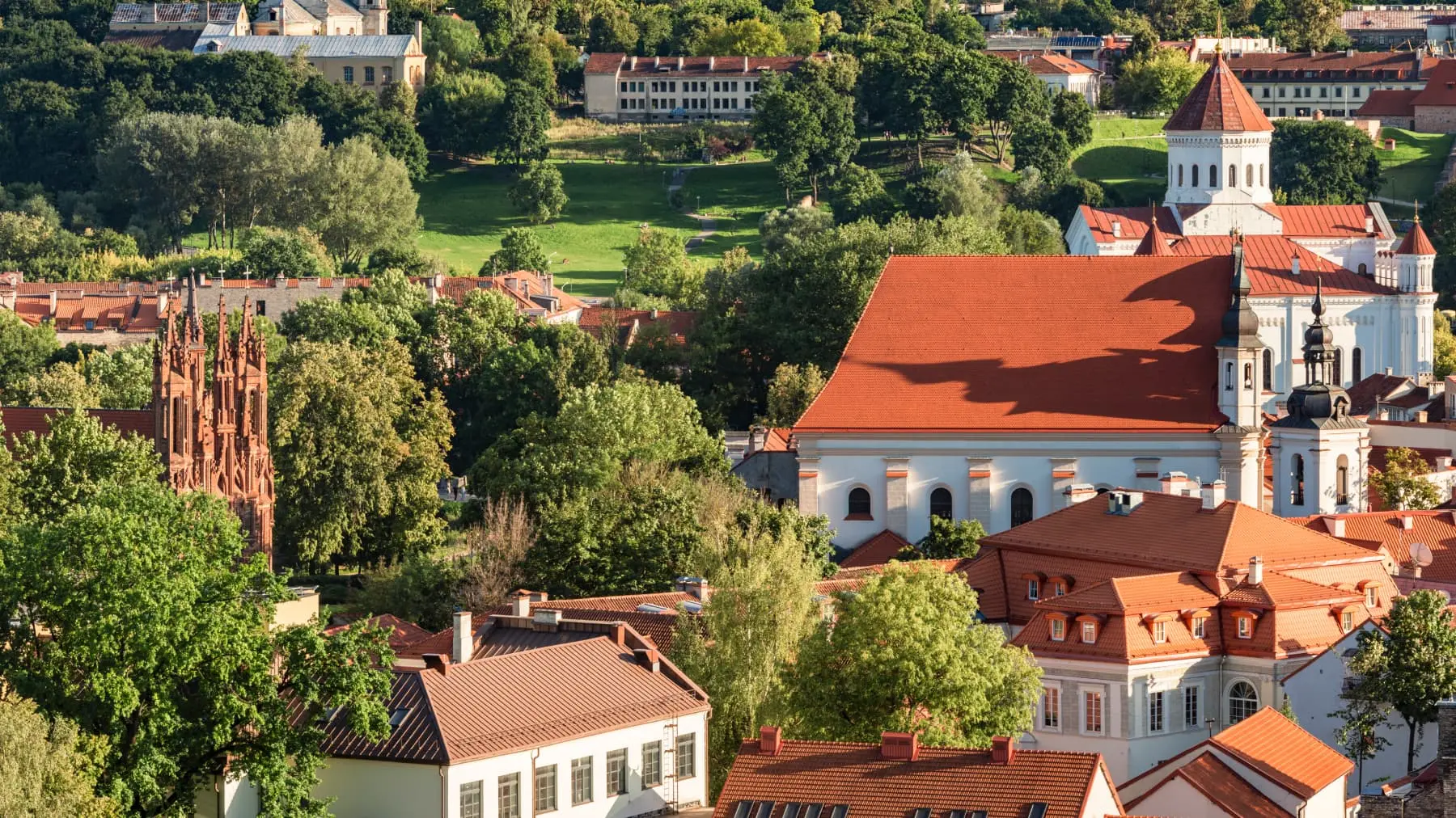 Aerial view of a historic Lithuanian town with orange tiled roofs and church spires.
