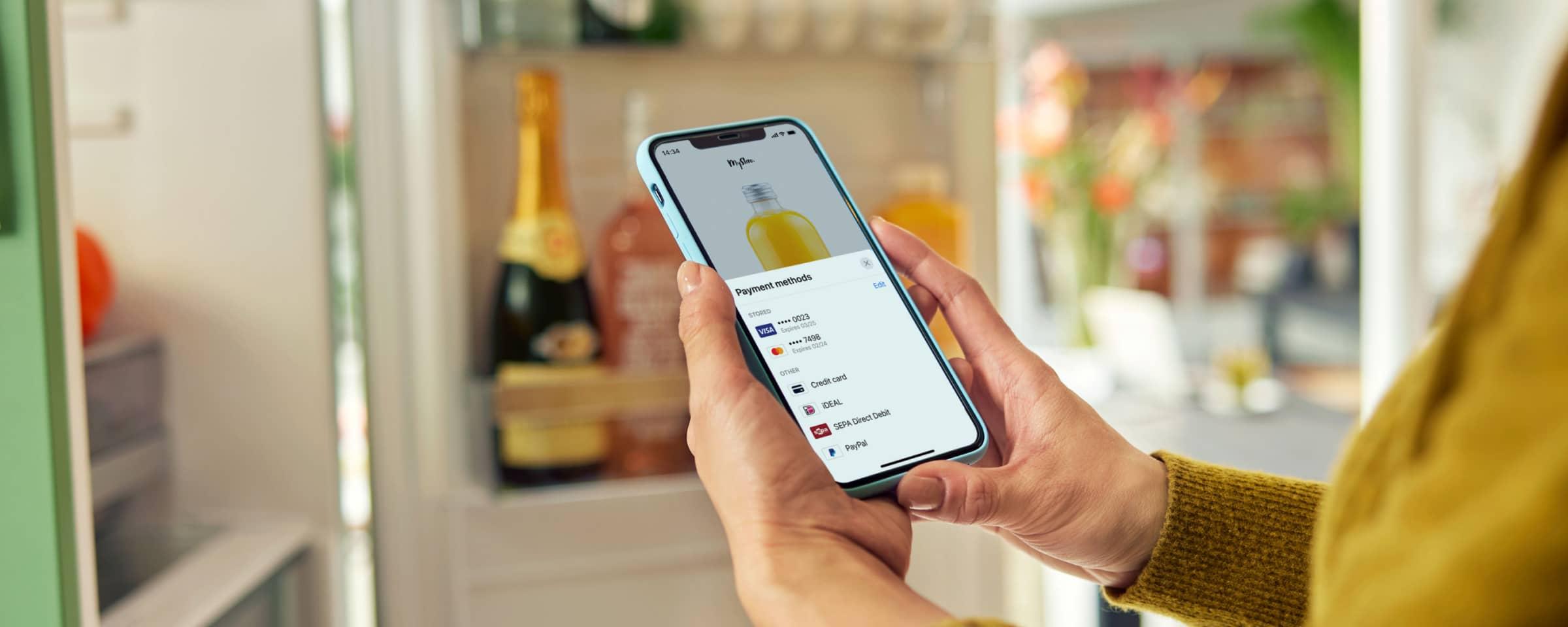 Persona que sostiene un smartphone con la pantalla de métodos de pago de Adyen.