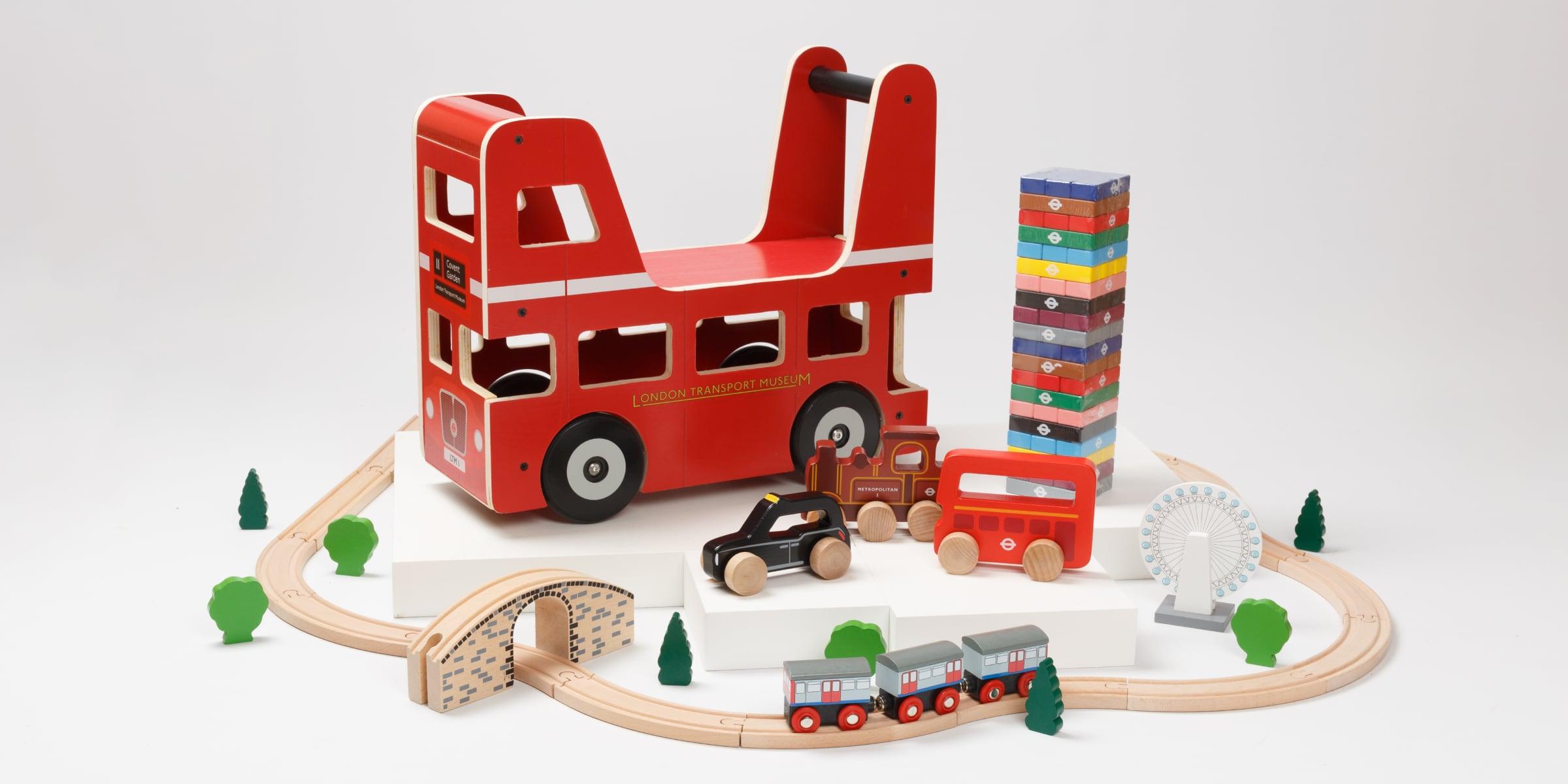 Wooden toy set with London bus, train tracks, and multiple vehicles on a white background.