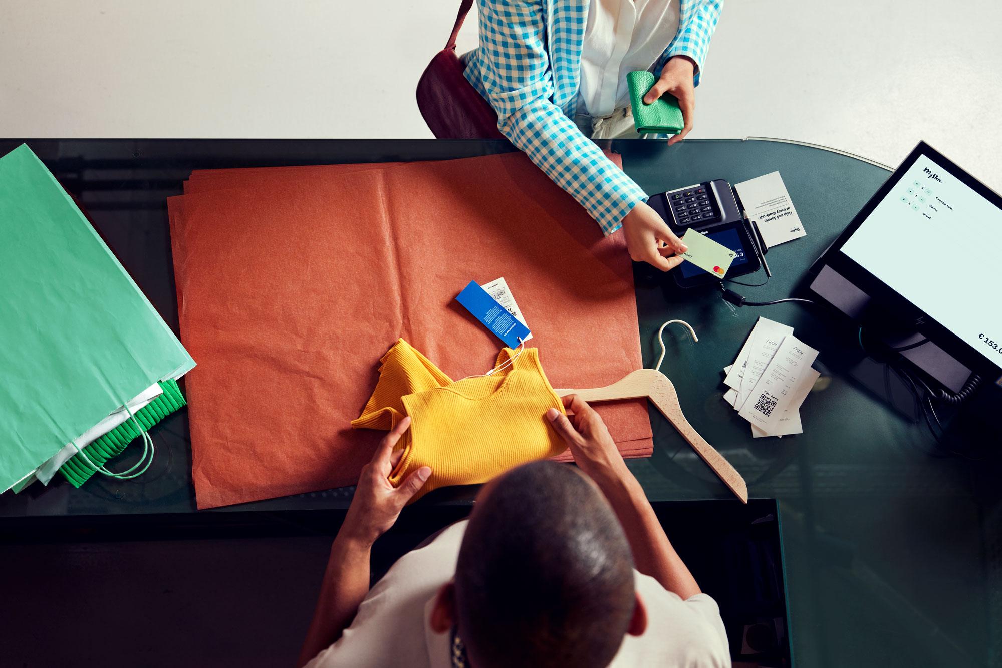A woman in a clothing store paying by tapping her card on Adyen's M400 terminal.