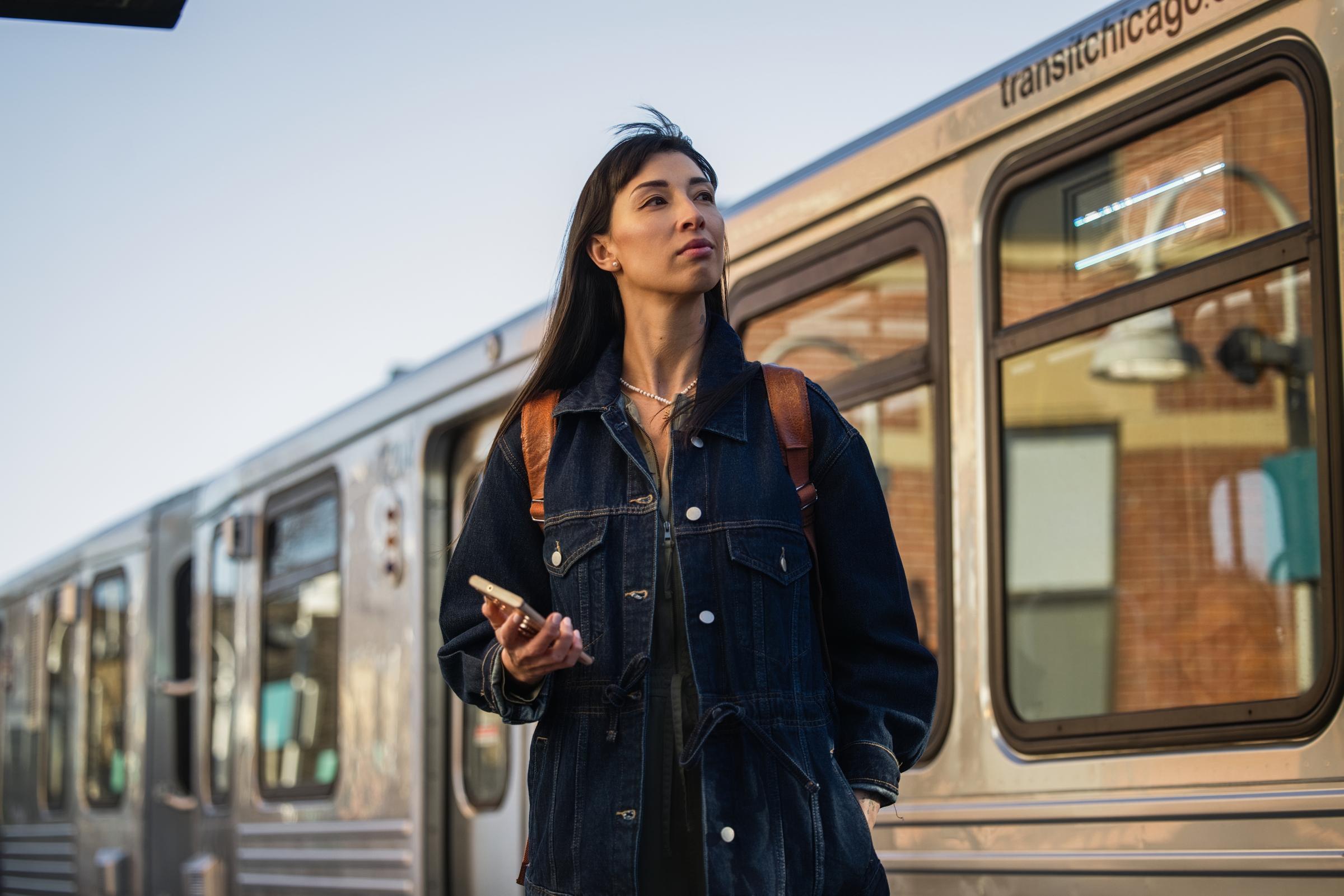 Traveler at a station using a mobile device near an Adyen payment terminal.