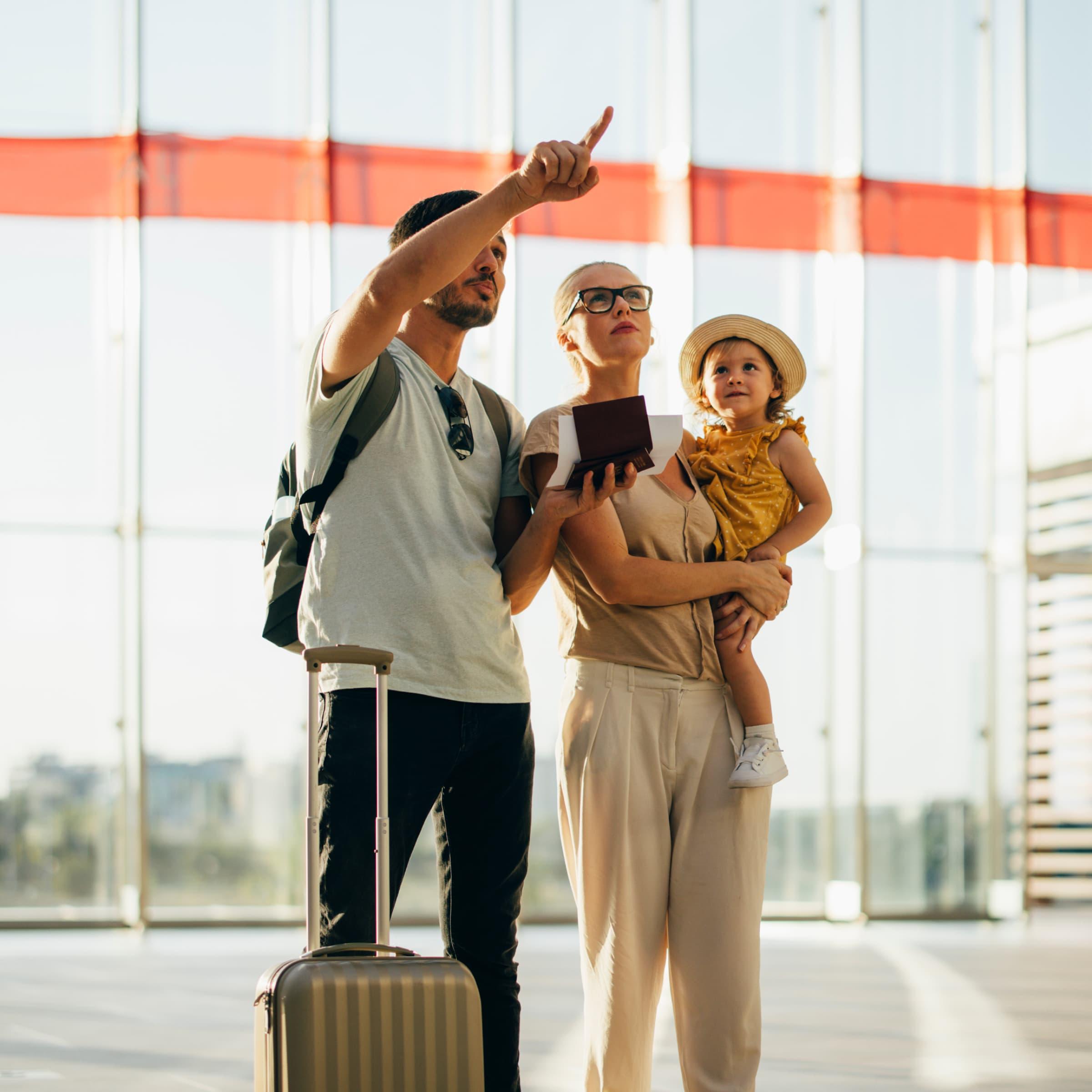 Family with luggage at the airport with father pointing something out.