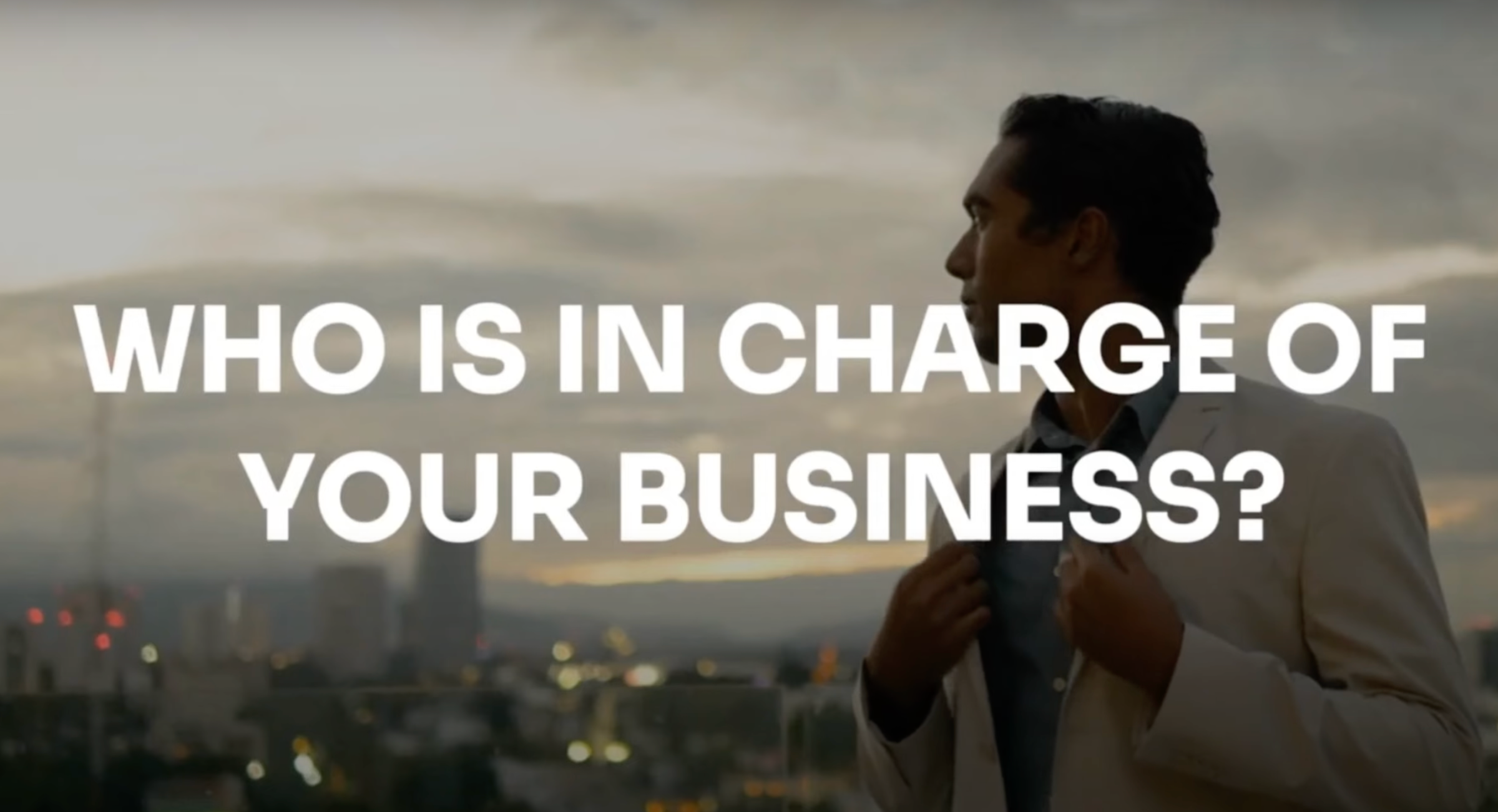 A business owner reflecting on leadership with a city skyline at sunset.