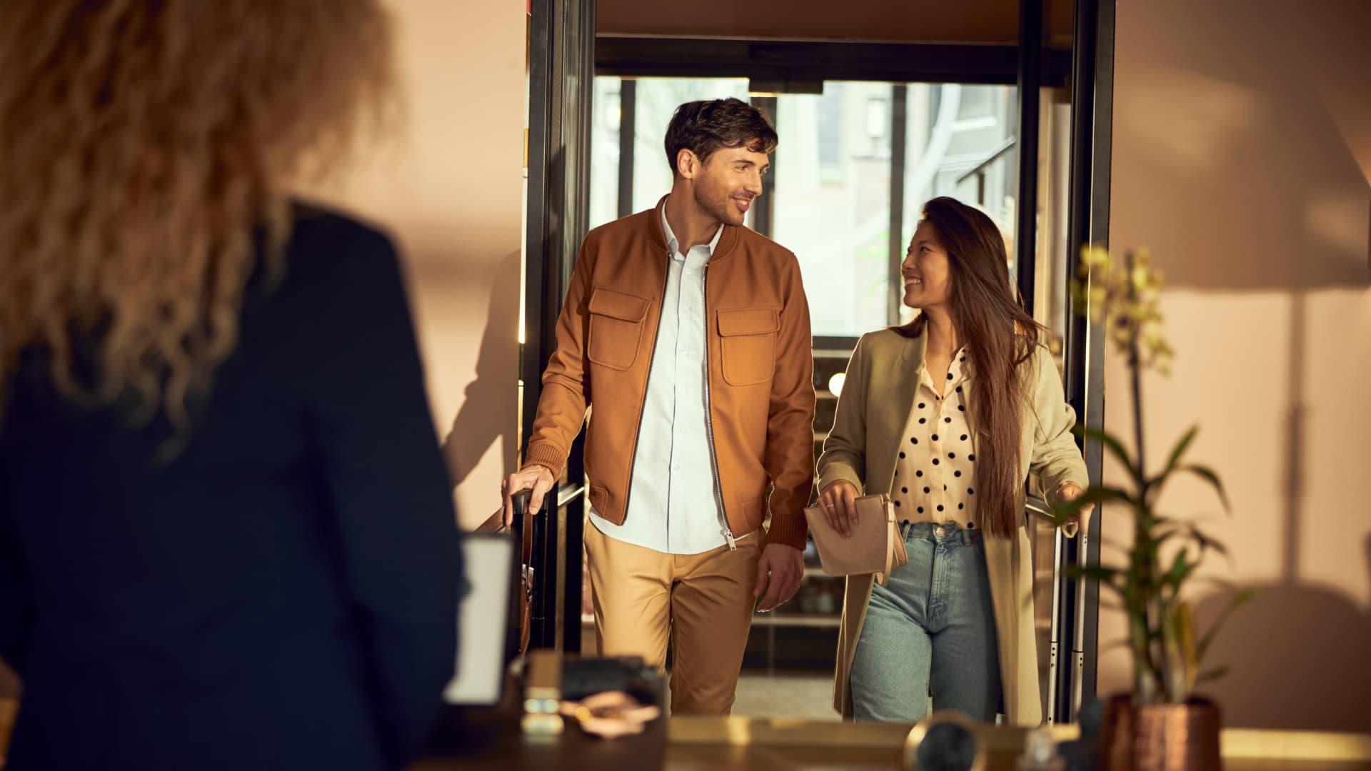 Två personer går lyckligt ut ur en byggnad med en som håller en väska