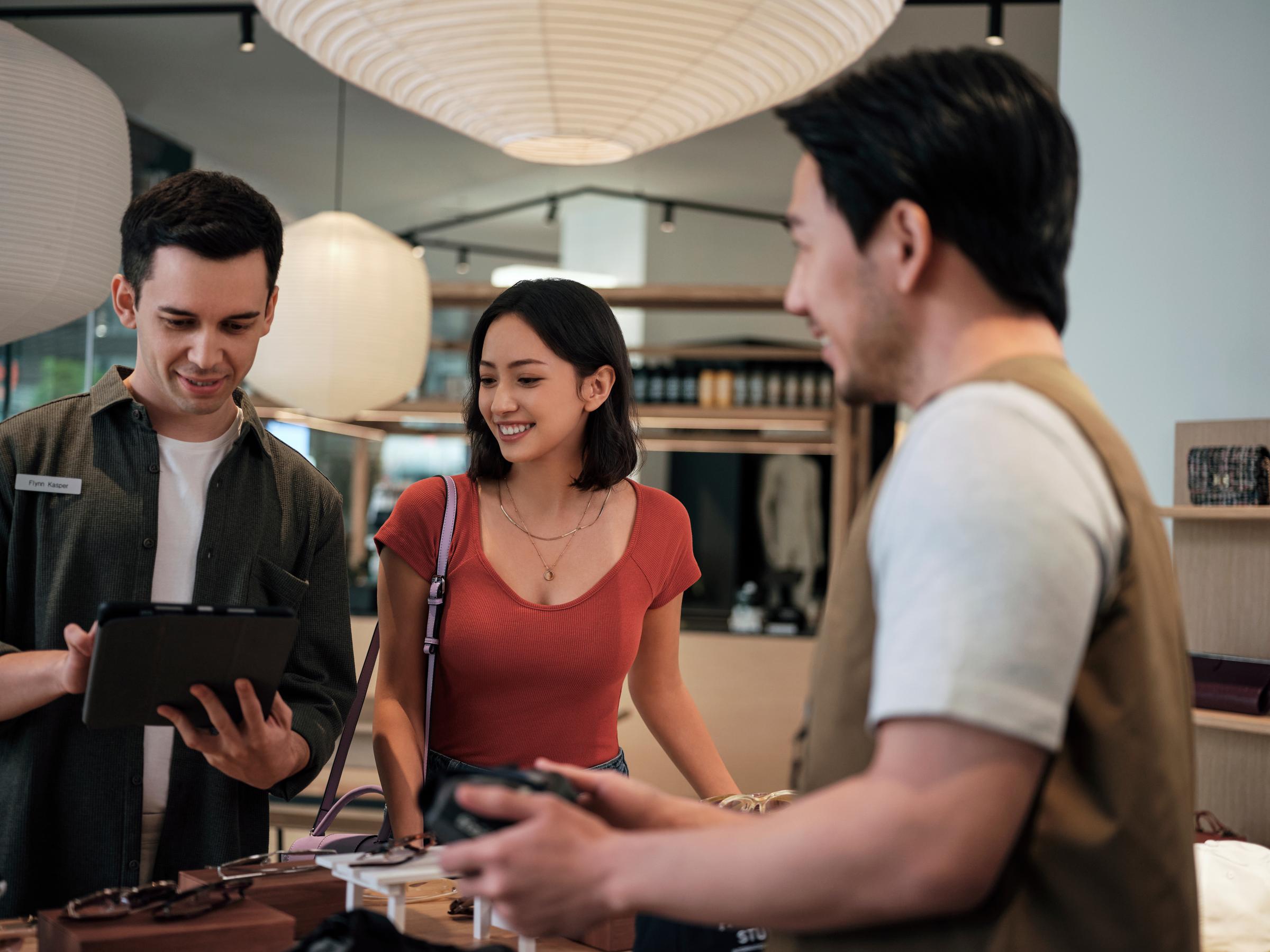 Asian couple getting assistance from shop staff holding iPad