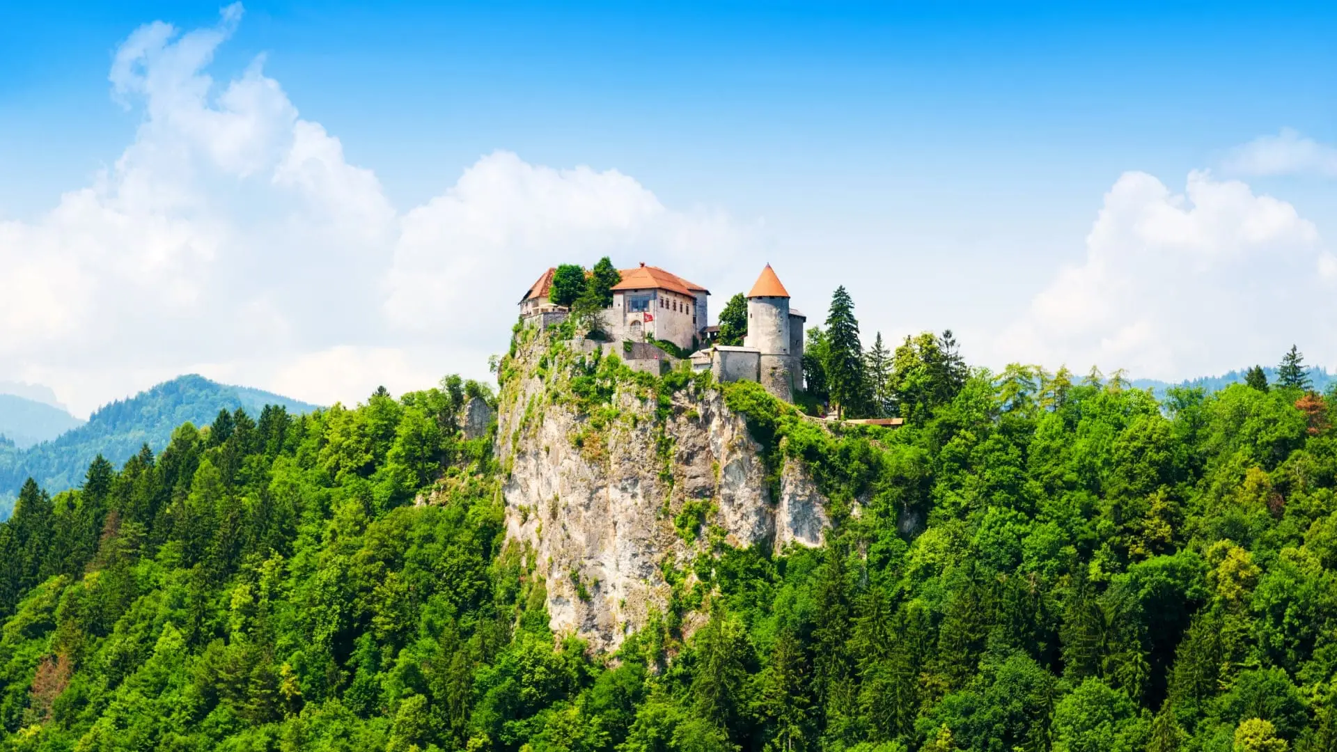 A castle located on a rocky slope overseeing a green forest in Slovakia.