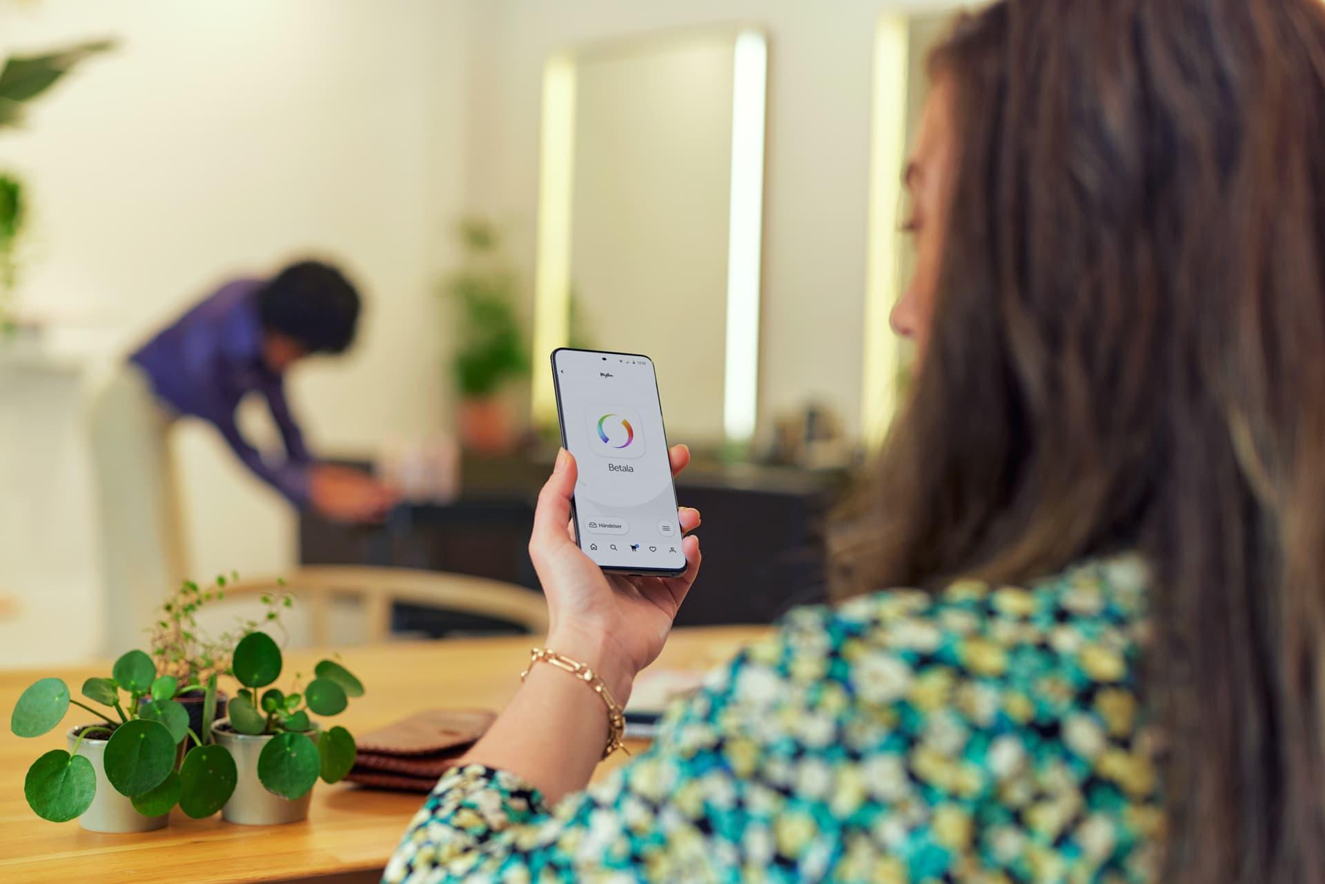 Person som håller i en smartphone med Adyen-betalningsappen på skärmen.