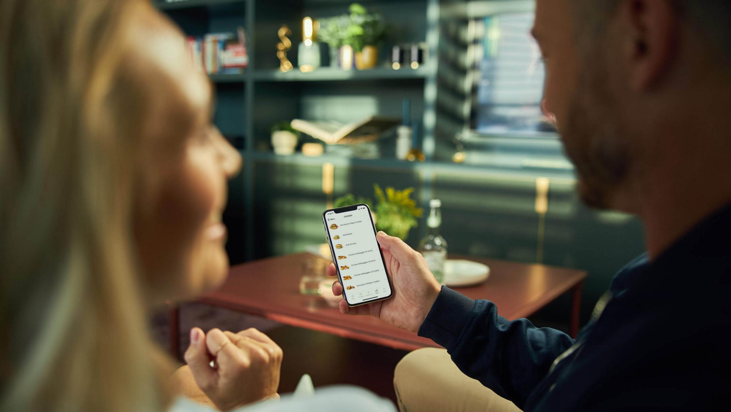 Two people looking at a mobile payment app over dinner in a cozy setting.