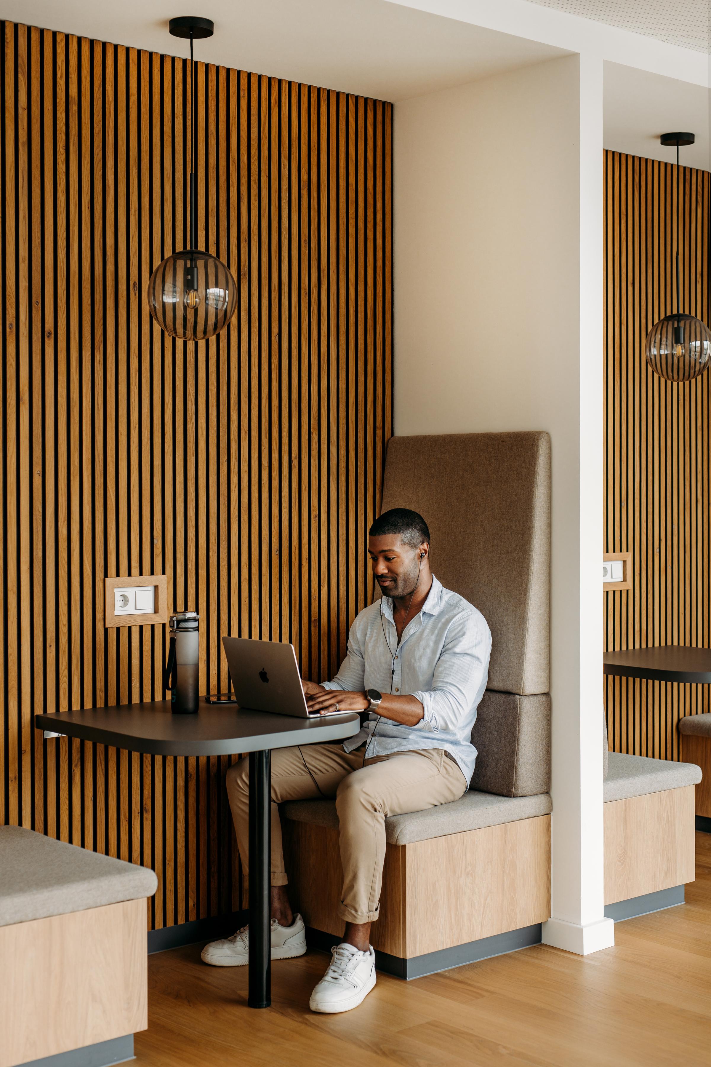 A man sitting on a small sofa behind his laptop 