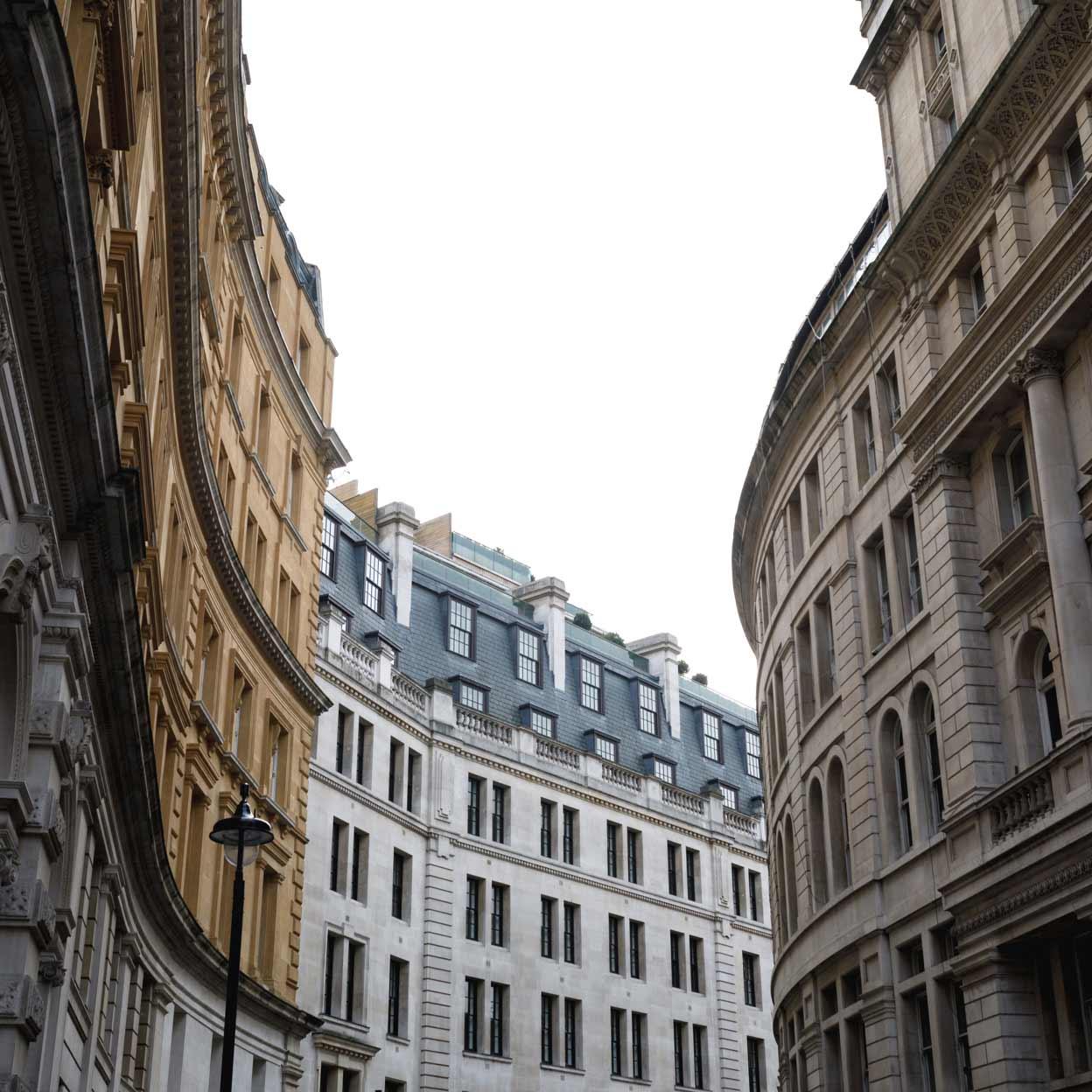 Gekrümmte Londoner Straße mit klassischer Architektur und bewölktem Himmel