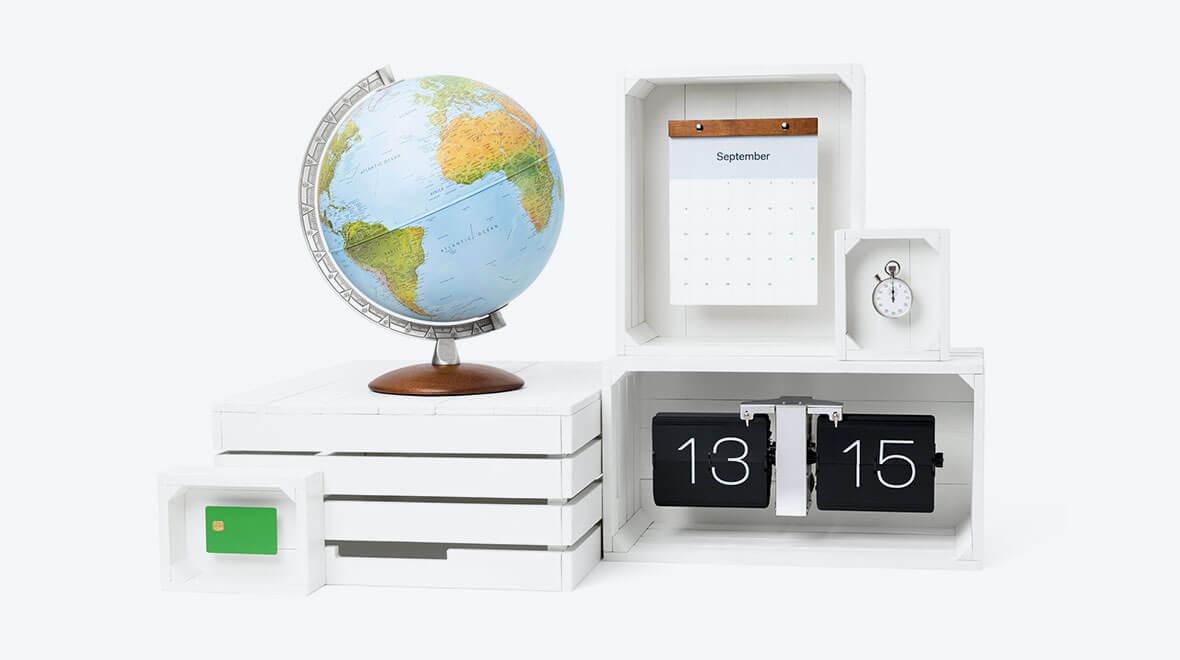 Desk setup with a wooden globe, flip calendar showing the date 13th and 15th, and a small green Adyen payment card.