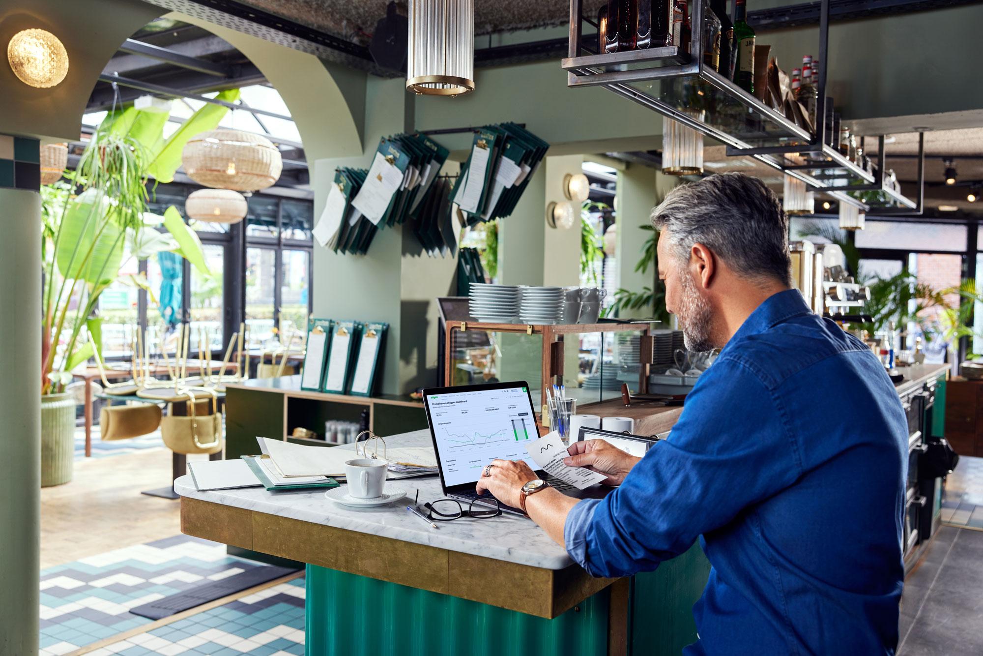 Restaurant employee looking at a Adyen dashboard with data charts.