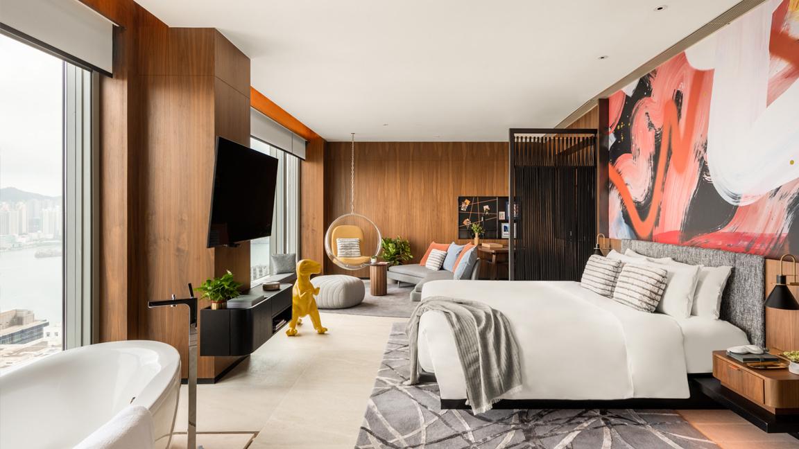 Modern bedroom interior with a large bed, hanging chair, and expansive city view through window.