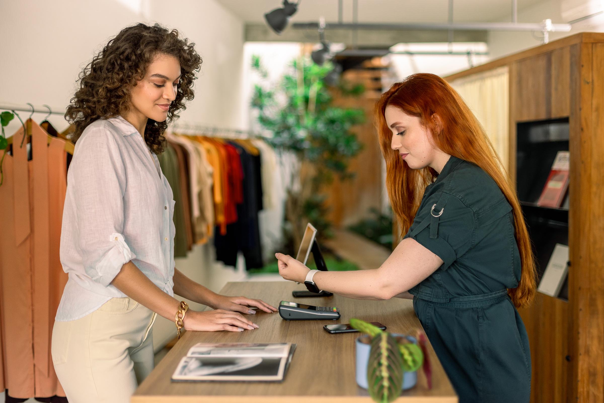 Person som betalar vid terminalen i en klädbutik med hjälp av en bärbar enhet