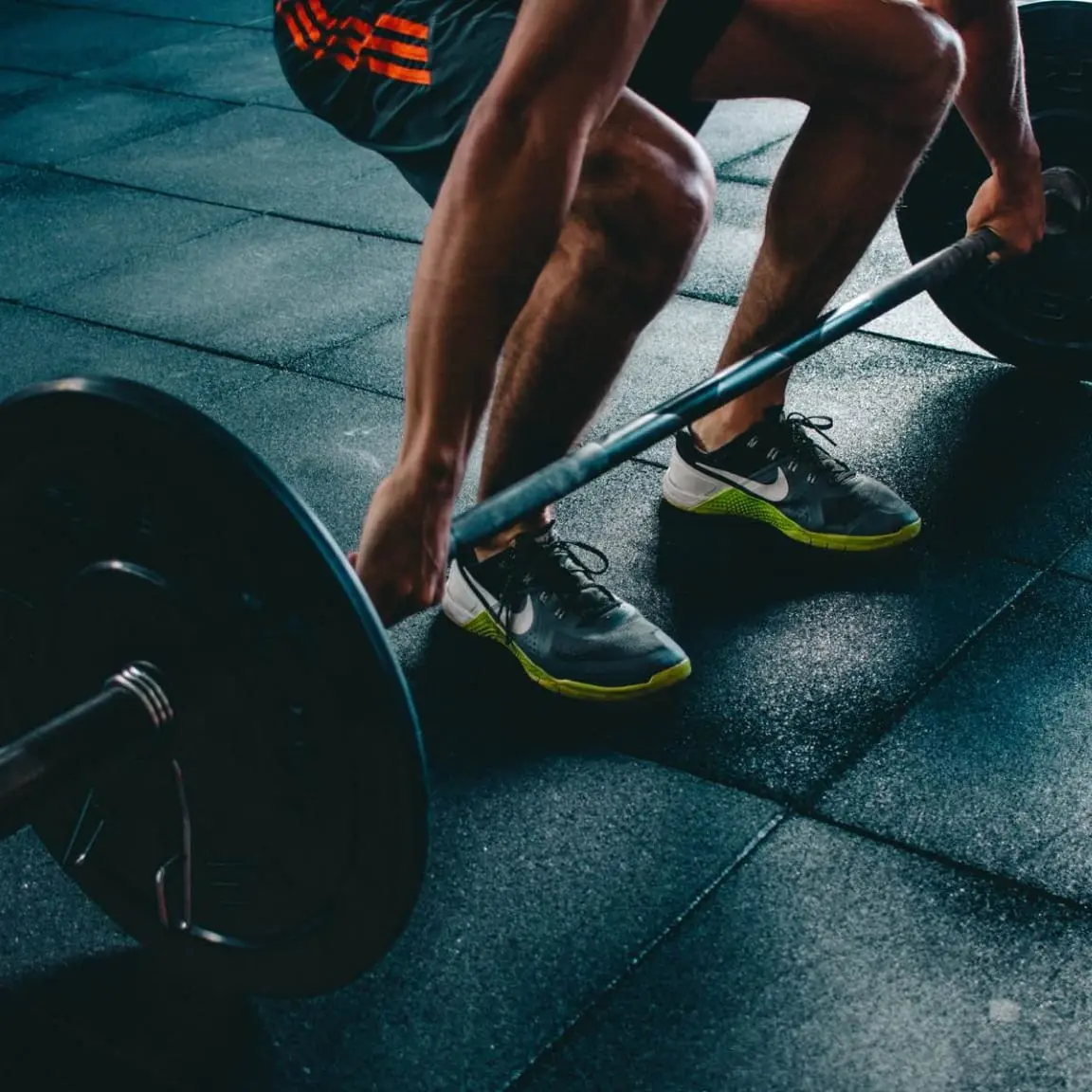 Nærbilde av en person som utfører en dødløft med en barbell på treningsstudio