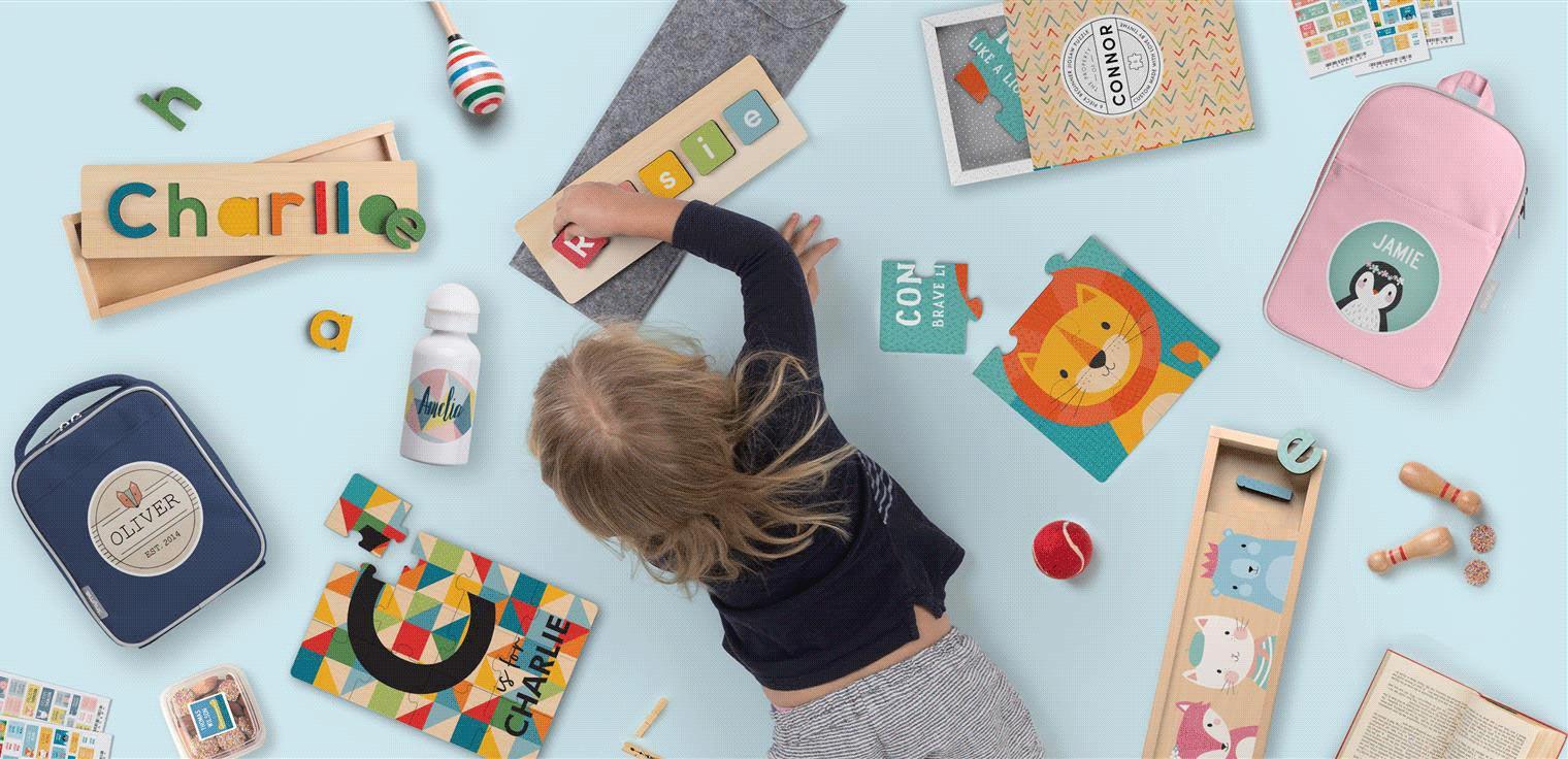 Child playing with alphabet puzzle next to customized items with children's names.
